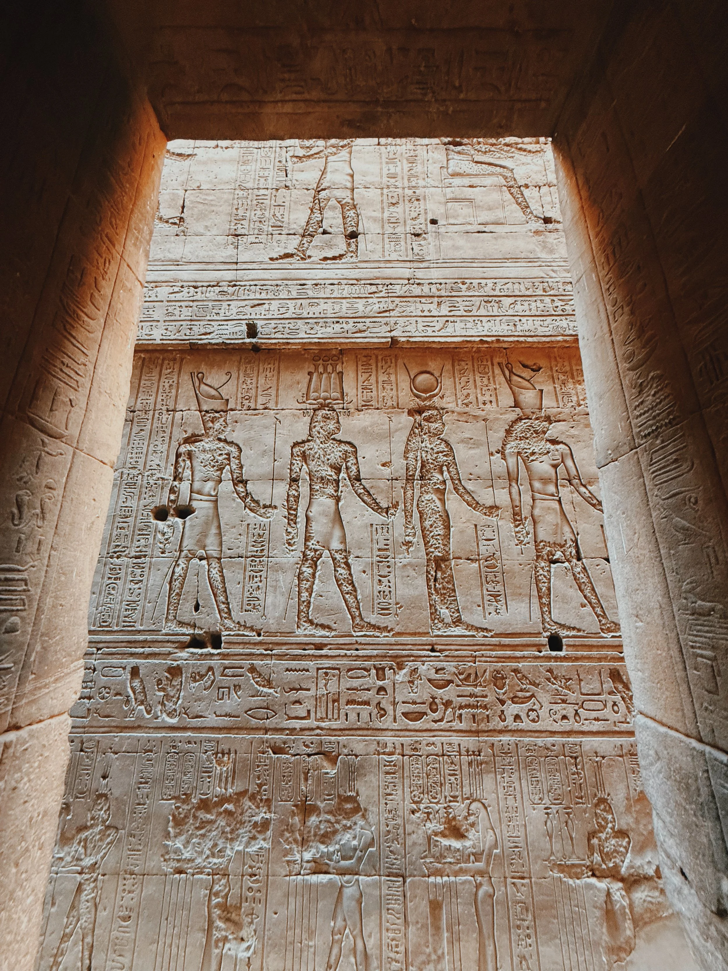 Looking up at towering carved walls and a strip of blue sky inside the Temple of Horus at Edfu.