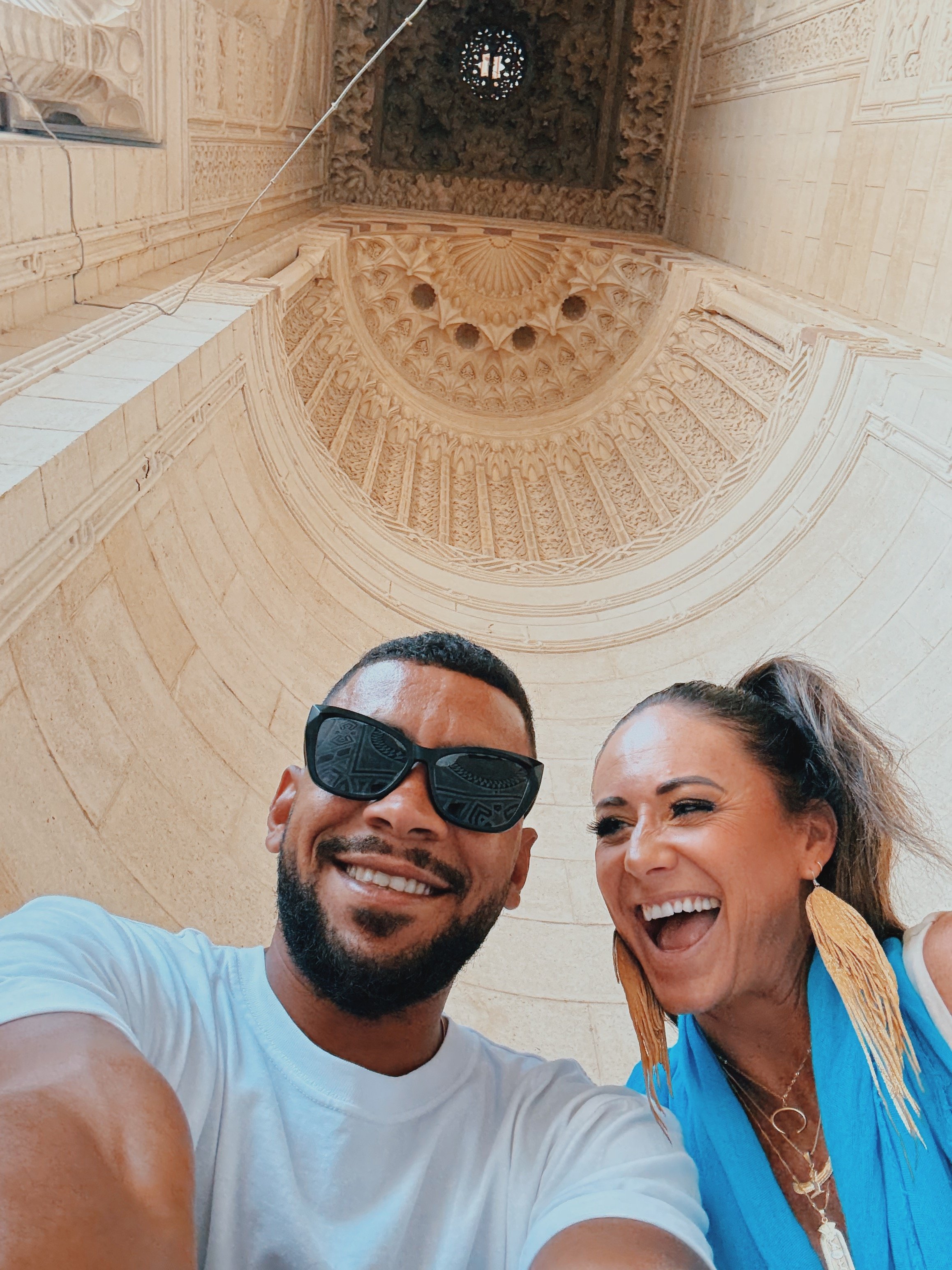 Jennifer and Mostafa of Takemet Tours laughing beneath the carved portal of the Abu al-Abbas al-Mursi Mosque in Alexandria