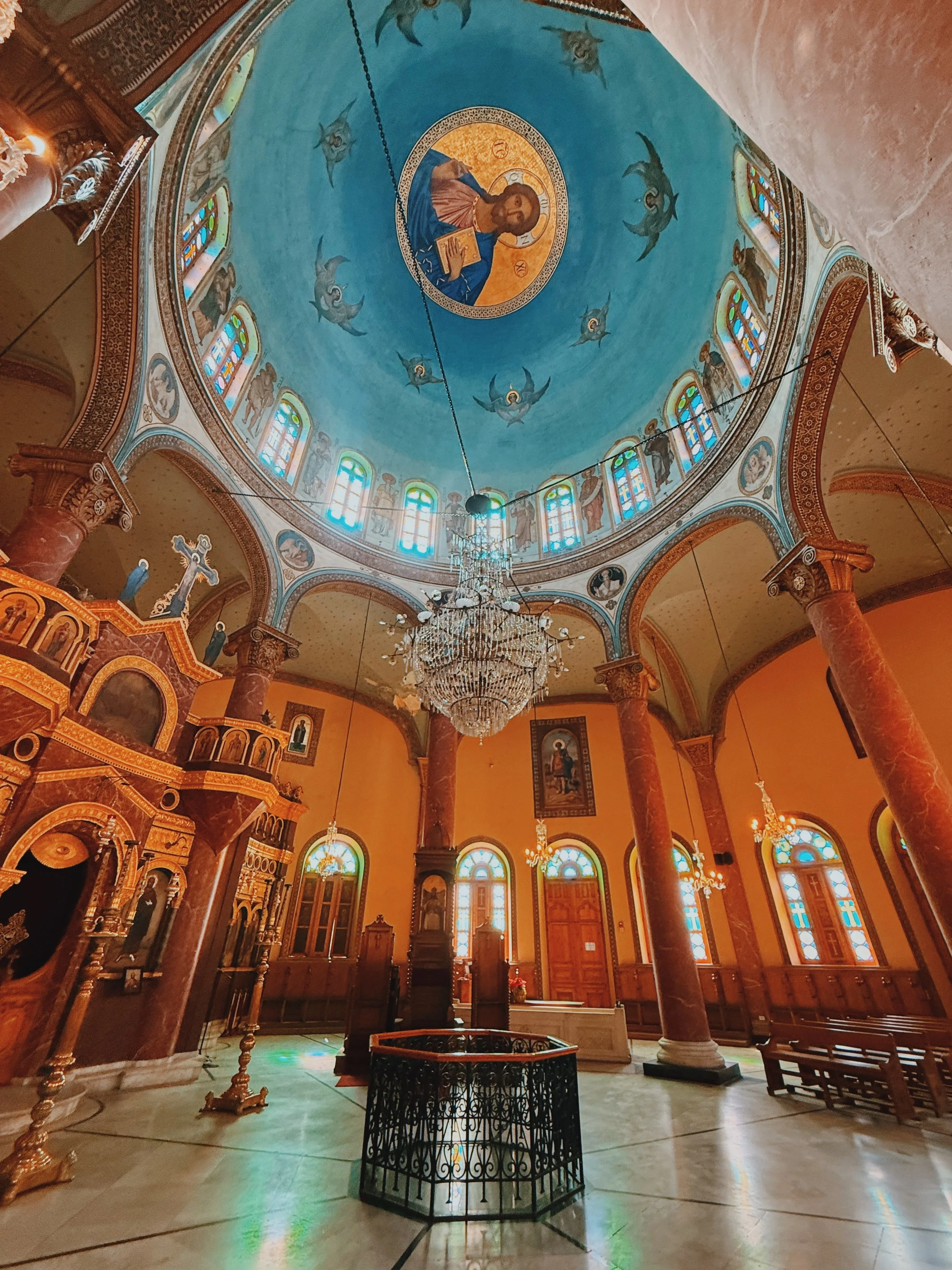 The round interior of the Church of St. George in Coptic Cairo, with marble columns, a crystal chandelier and a painted blue dome.