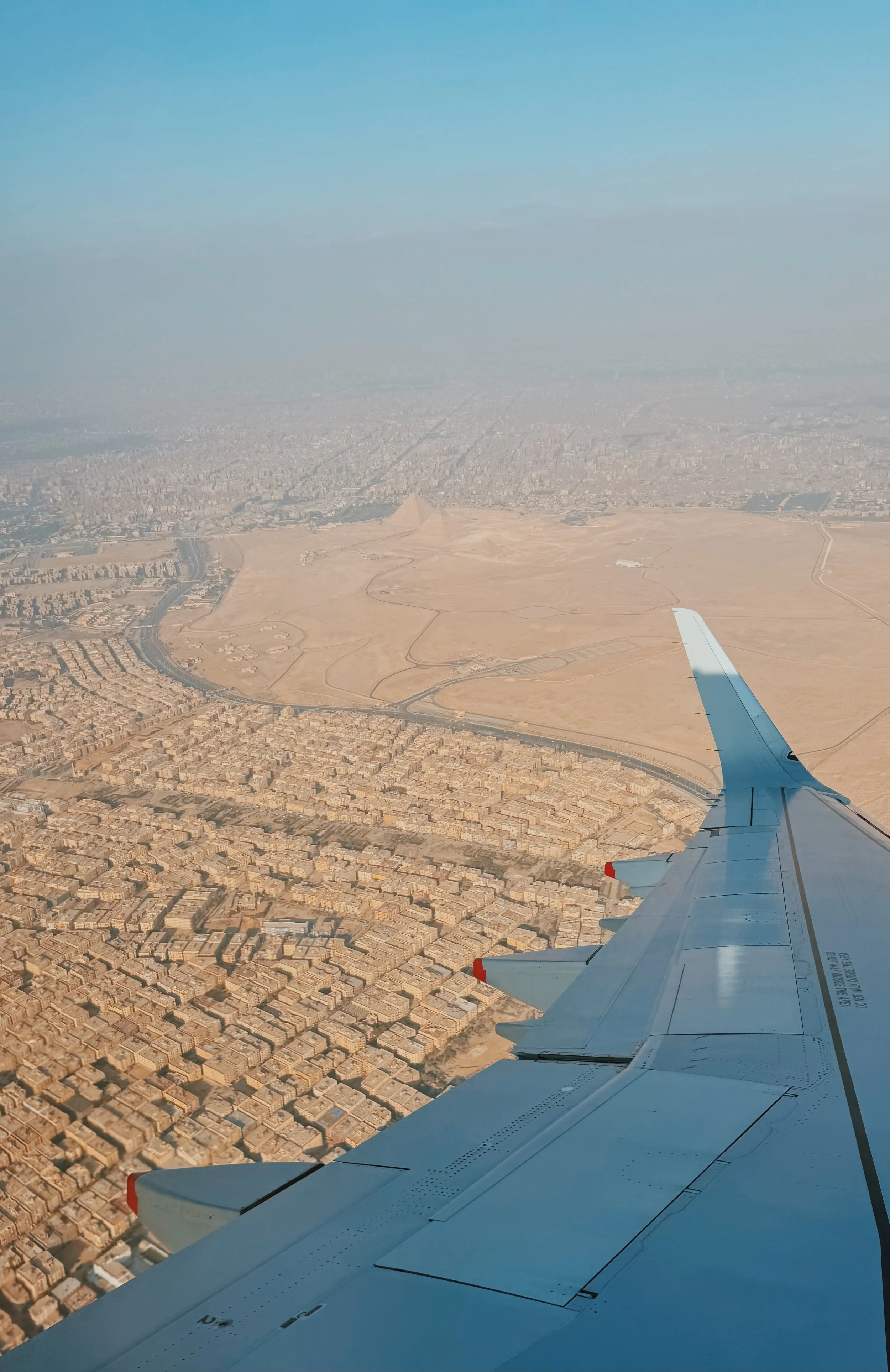The Pyramids of Giza and the edge of Cairo seen from an airplane window.
