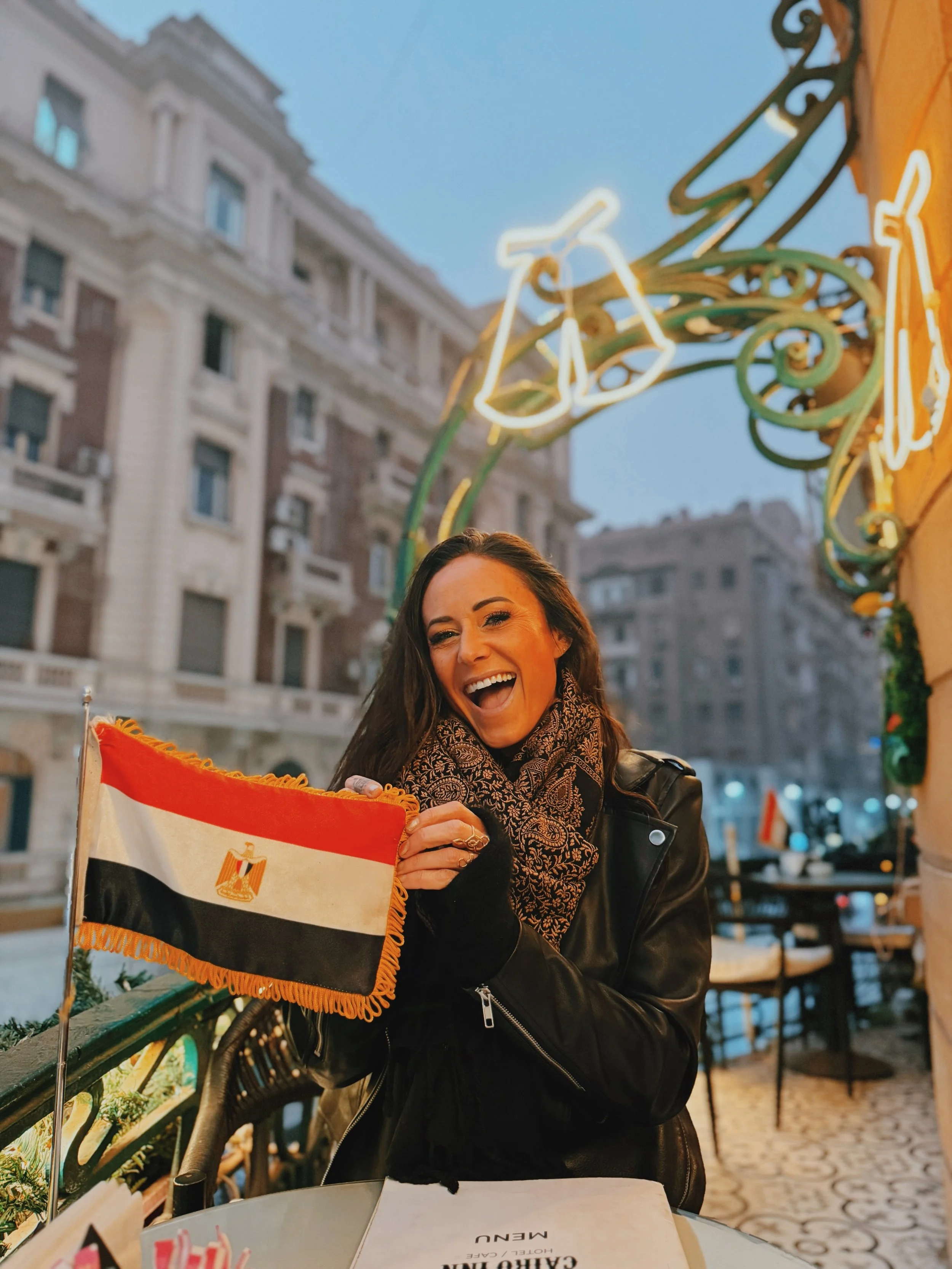 Jennifer of Takemet Tours  laughing and holding an Egyptian flag at the Cairo Inn café in Downtown Cairo