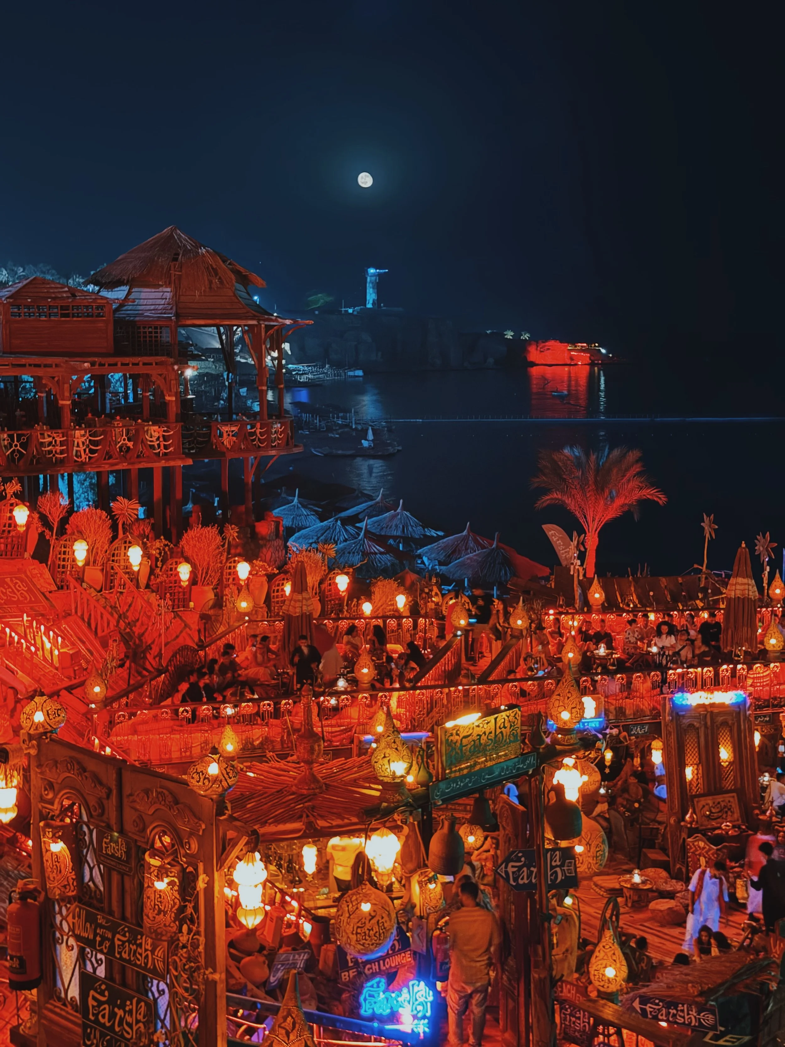Lantern-lit terraces of Farsha café glowing beneath a full moon over the bay in Sharm El Sheikh.
