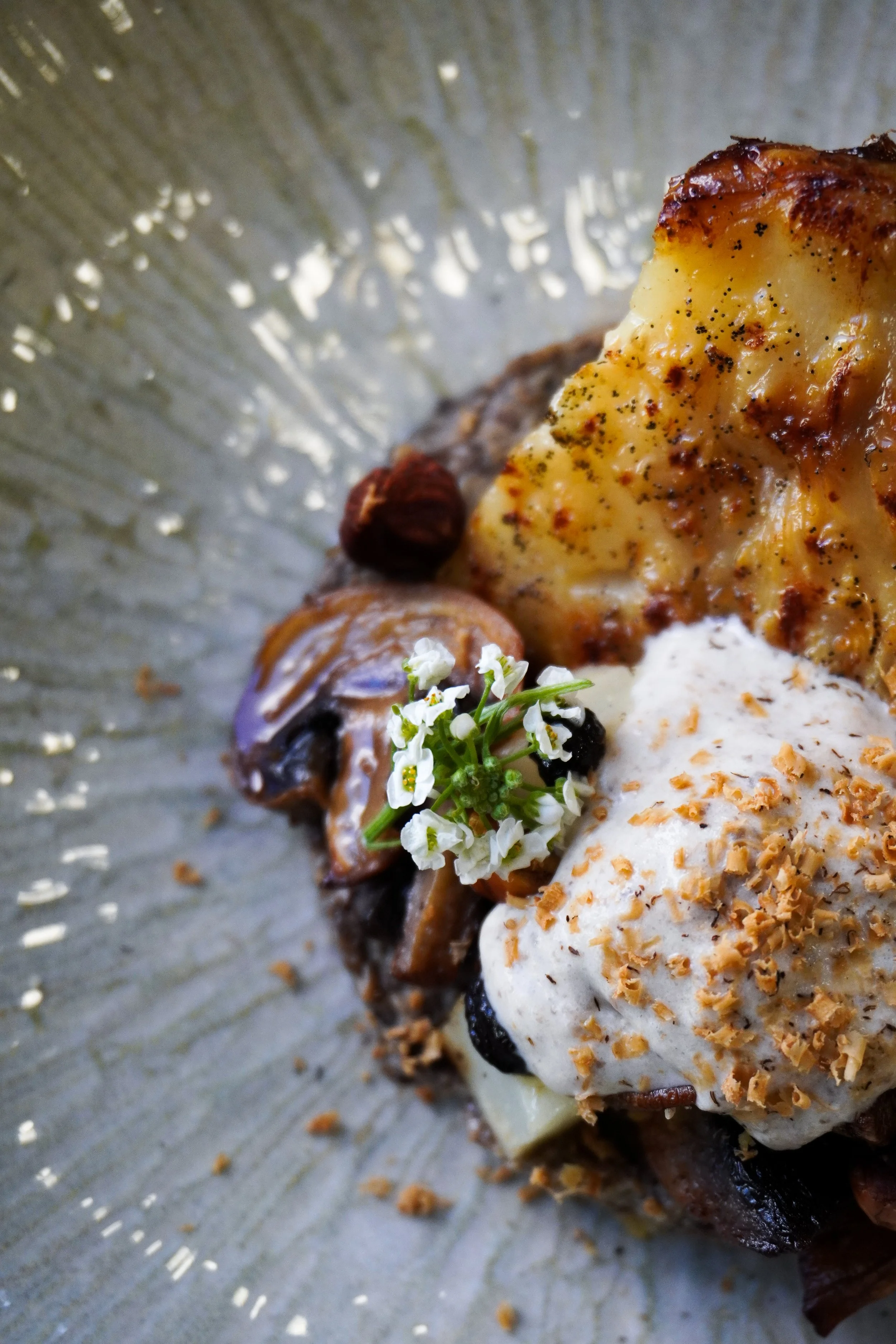 Plat gastronomique avec fruits de mer, légumes, herbes et sauce, présenté dans une assiette à décoration fine.