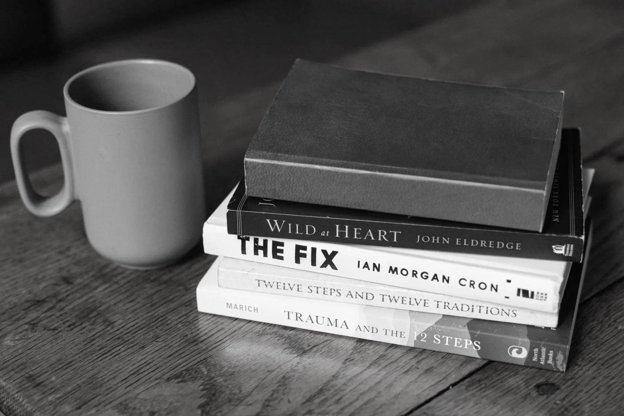 Therapy books on recovery and coping strategies placed on a table in a counseling office