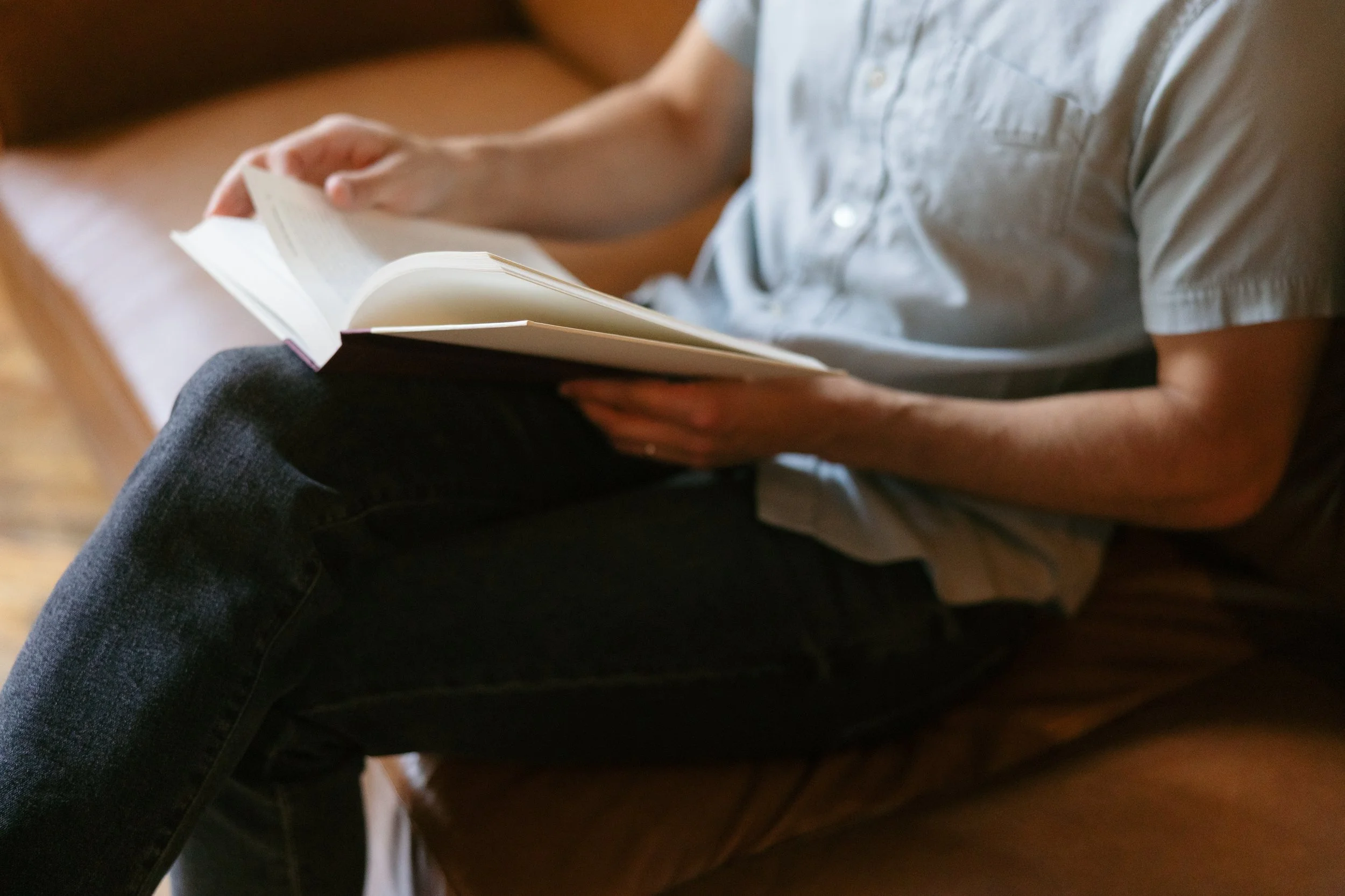 Therapist reading a book on a couch, representing couples counseling in Nashville and Brentwood at Hanks Therapy Co., supporting partners with communication issues, conflict, emotional disconnection, trust-building, and relationship growth.