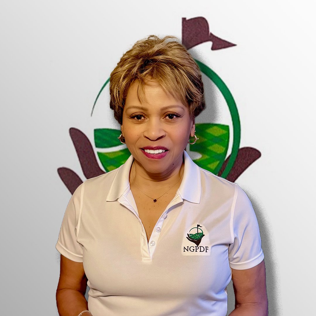 A woman with short, light brown hair smiling in front of a logo featuring a canoe and paddles, wearing a white polo shirt with the NGPDF logo.