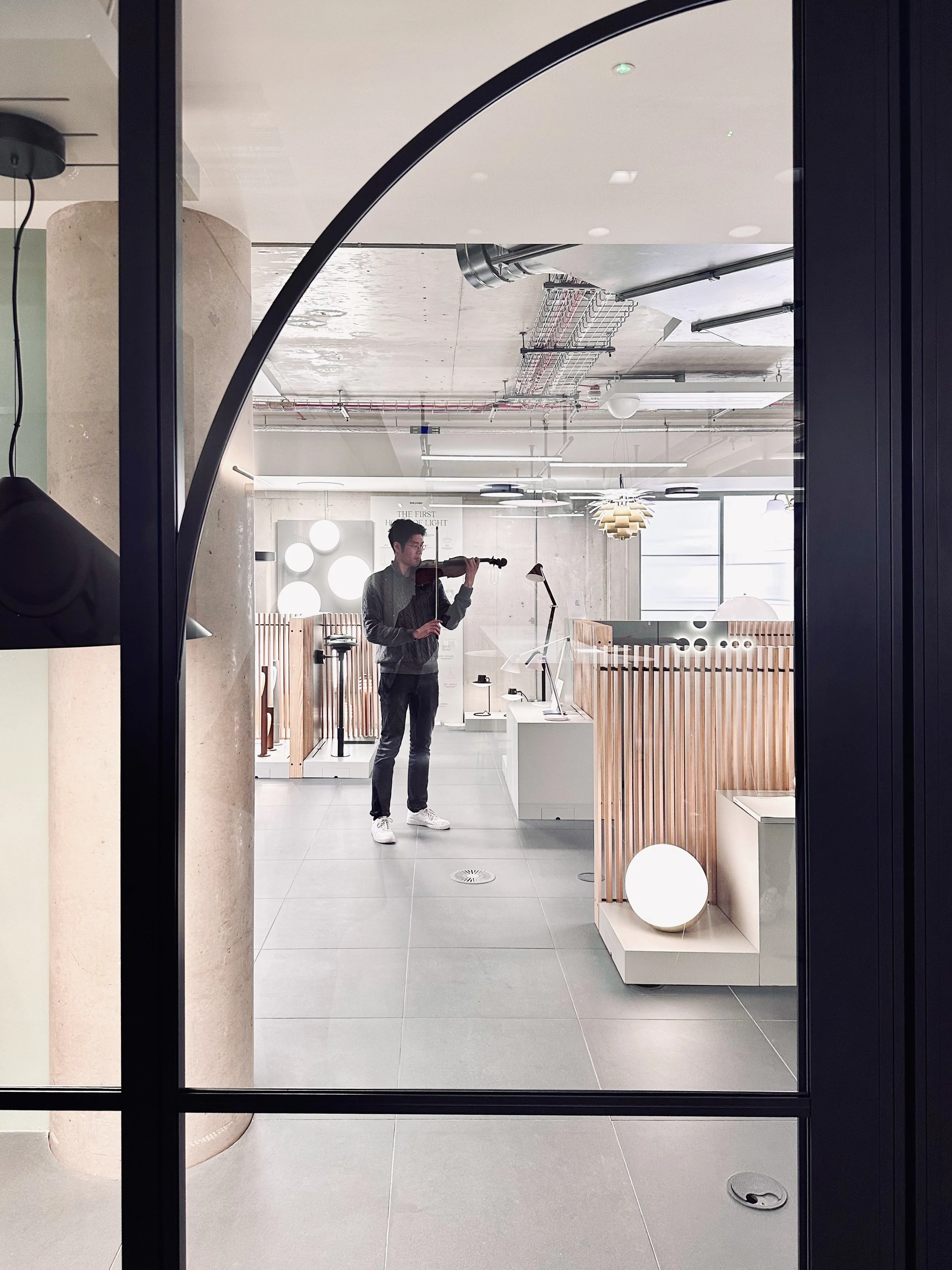 Black steel framed acoustic glazed partition by Optima in Tarisio’s London headquarters, with violinist playing in the space beyond