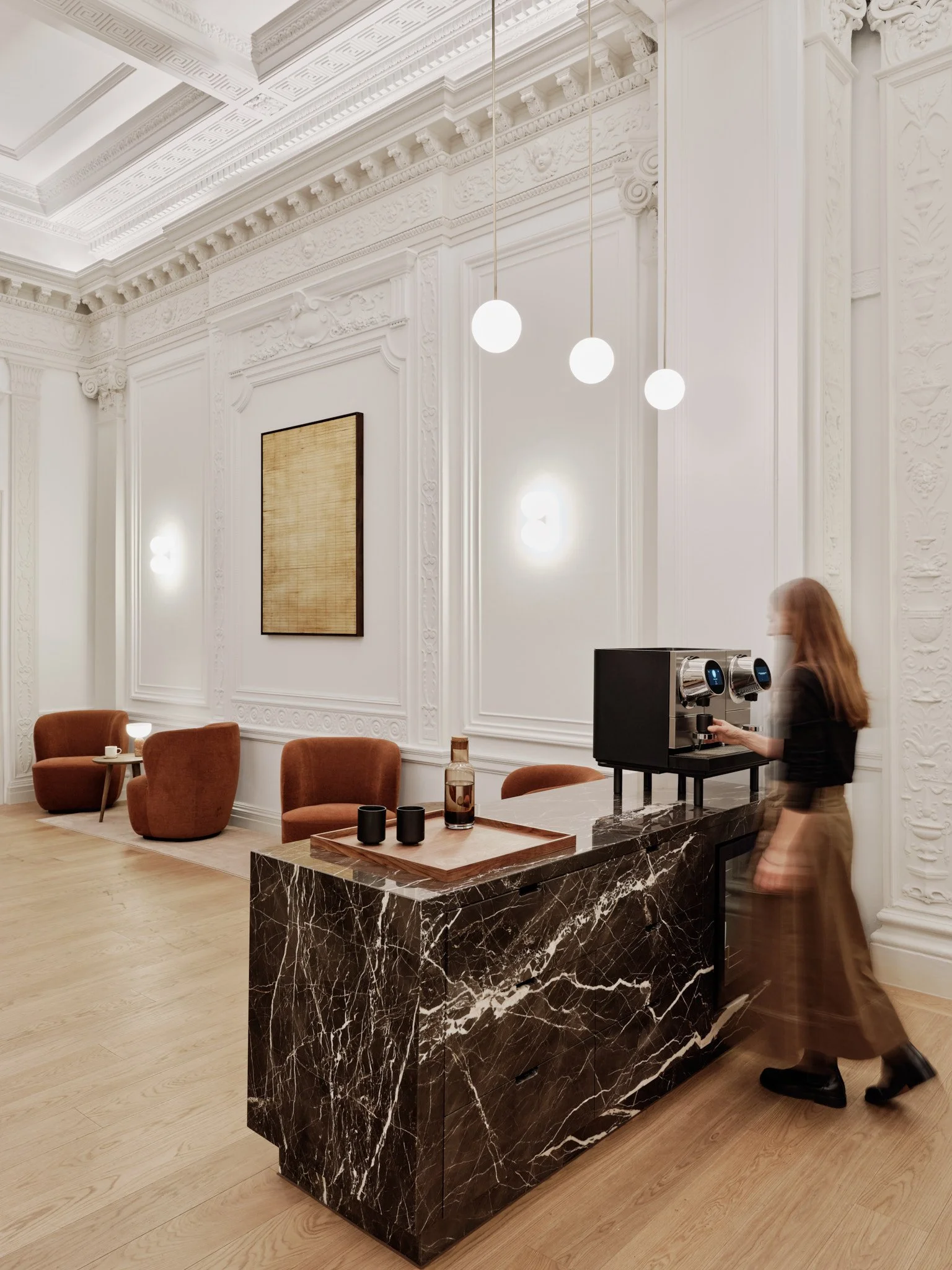 The black marble tenant coffee bar echos the reception desk while new polished brass pendant light drops visually divide the space. Cable runs from below are concealed behind MDF box outs at the adjacent pier and downstand.