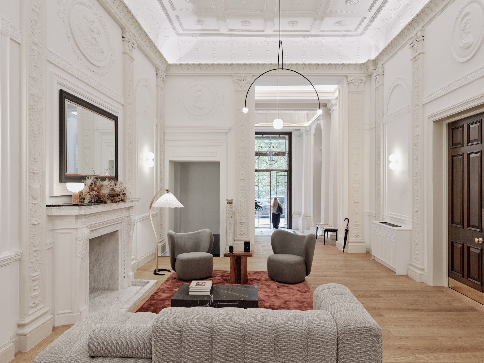 The grand existing fireplace now framed by symmetrical wall lights, acts as a central focus in the lounge area with new furniture specified by 4SA.