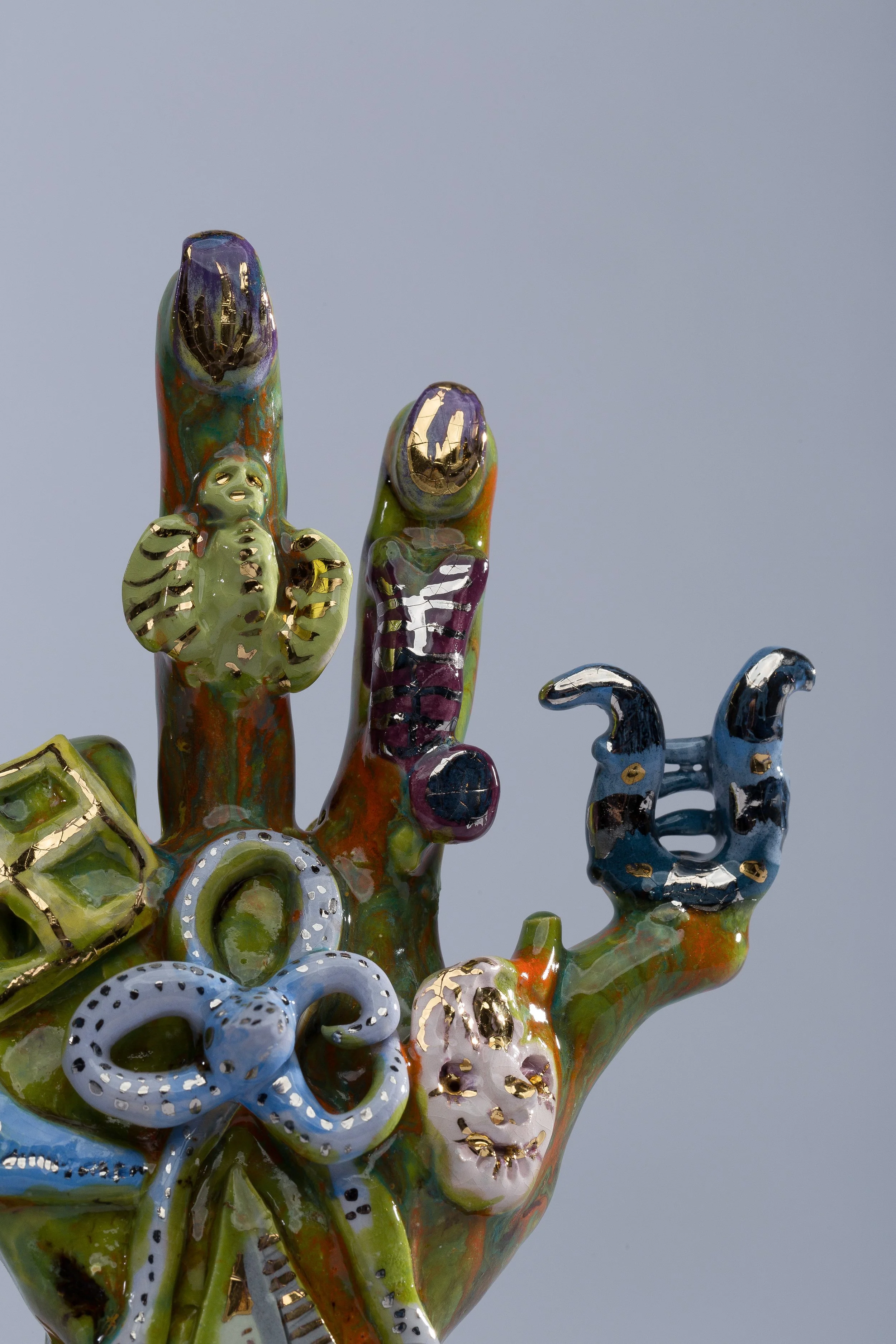 Colorful glass sculptures resembling cacti and desert plants with gold accents on a plain background.