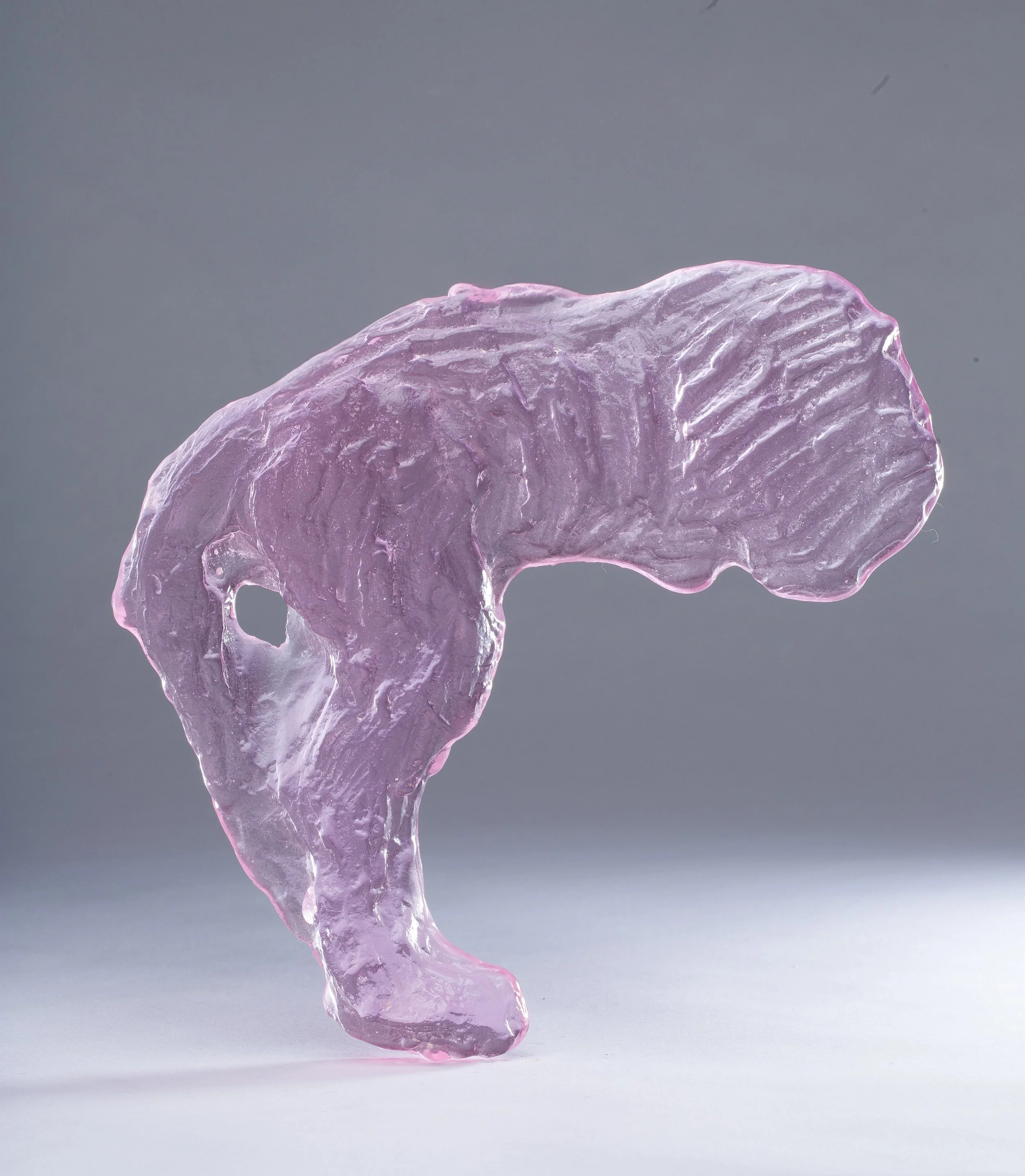 Close-up of a translucent pink ice sculpture with intricate textures against a gray background.