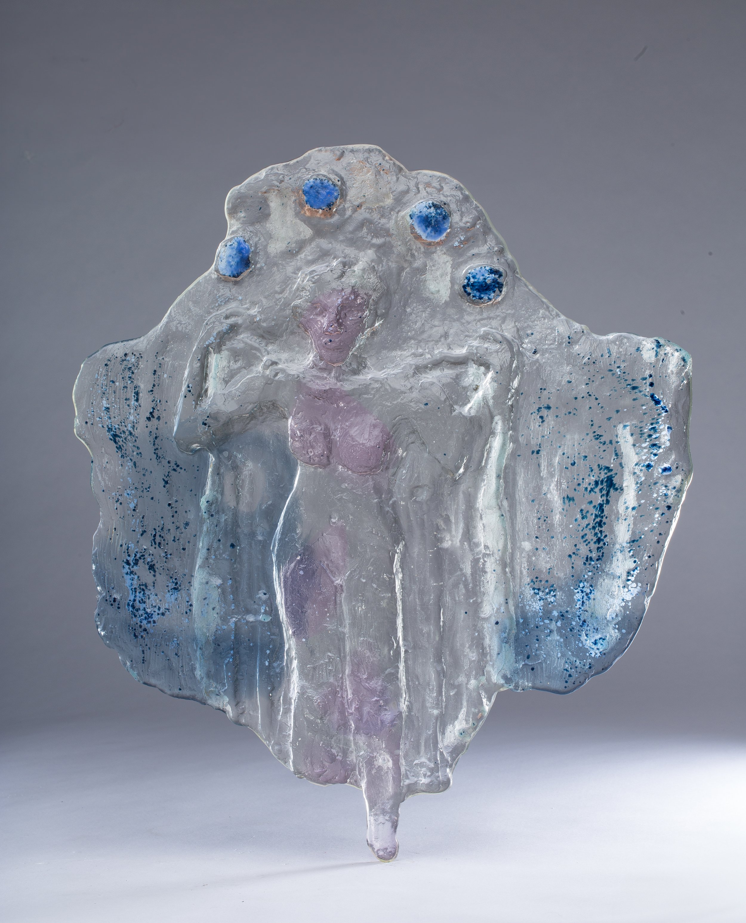 Close-up of an ice sculpture shaped like a tree with blue accents and a pinkish area in the center, against a neutral gray background.