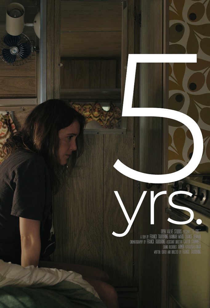 A woman with dark hair sitting on a bed near a wooden wall and cabinet, with large white text reading '5 yrs.' overlaid on the image.