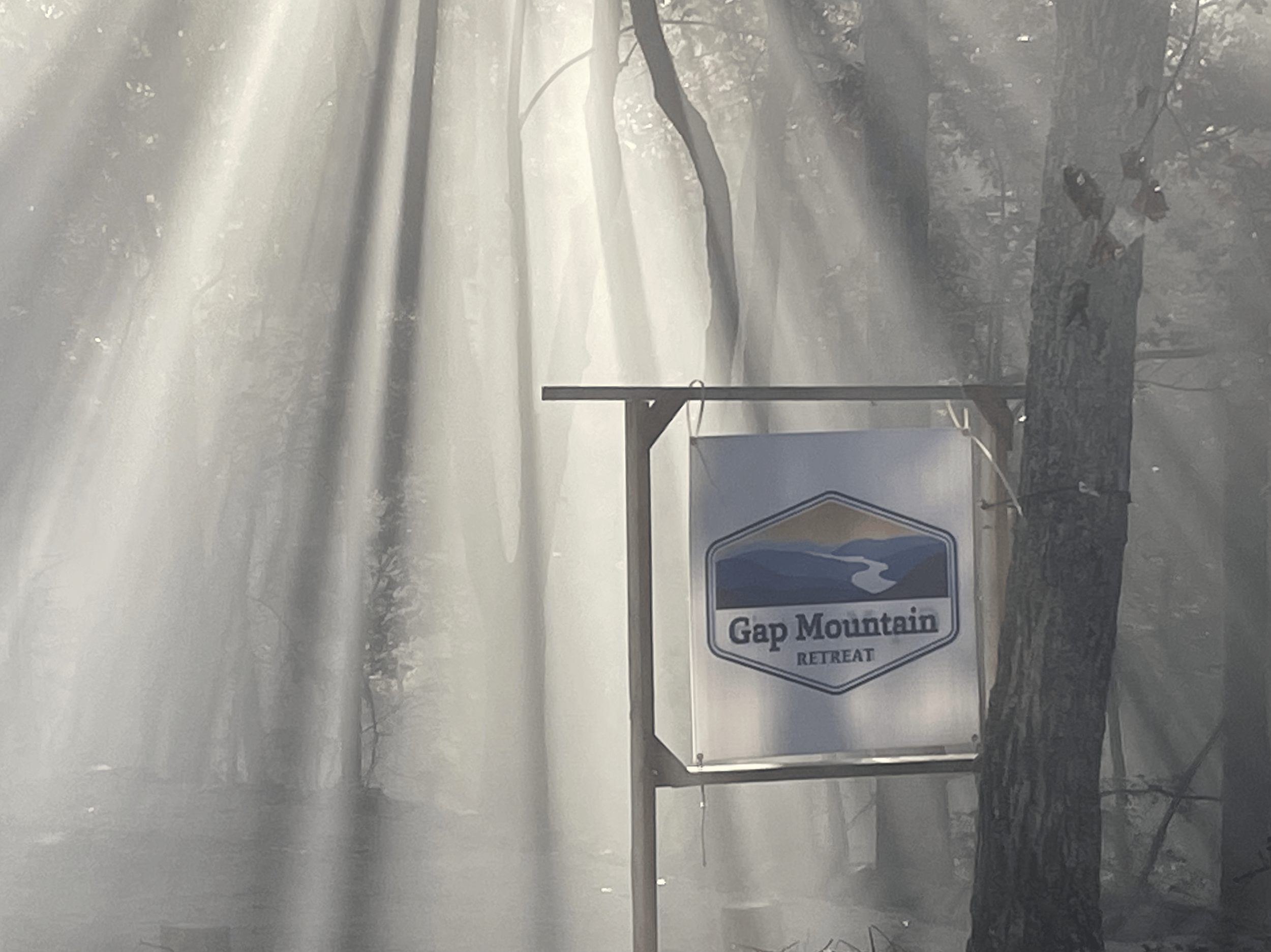 A foggy scene of trees along a road with a state park sign reading "Gap Mountain Retreat."