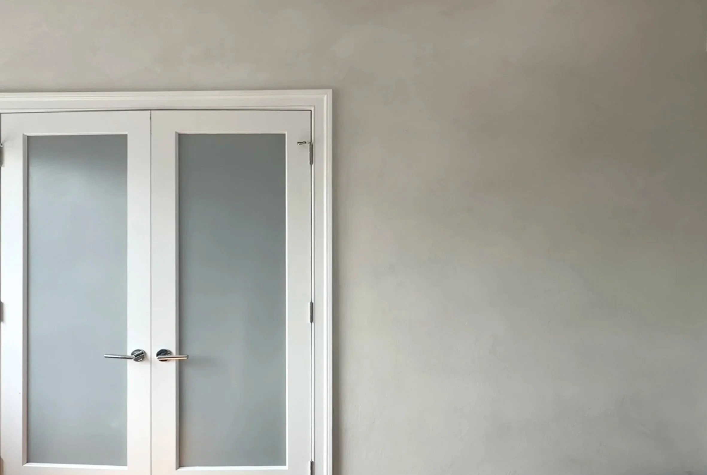Hand-applied cool gray limewashed wall beside white frosted-glass doors — West Village, Limewall & Co.