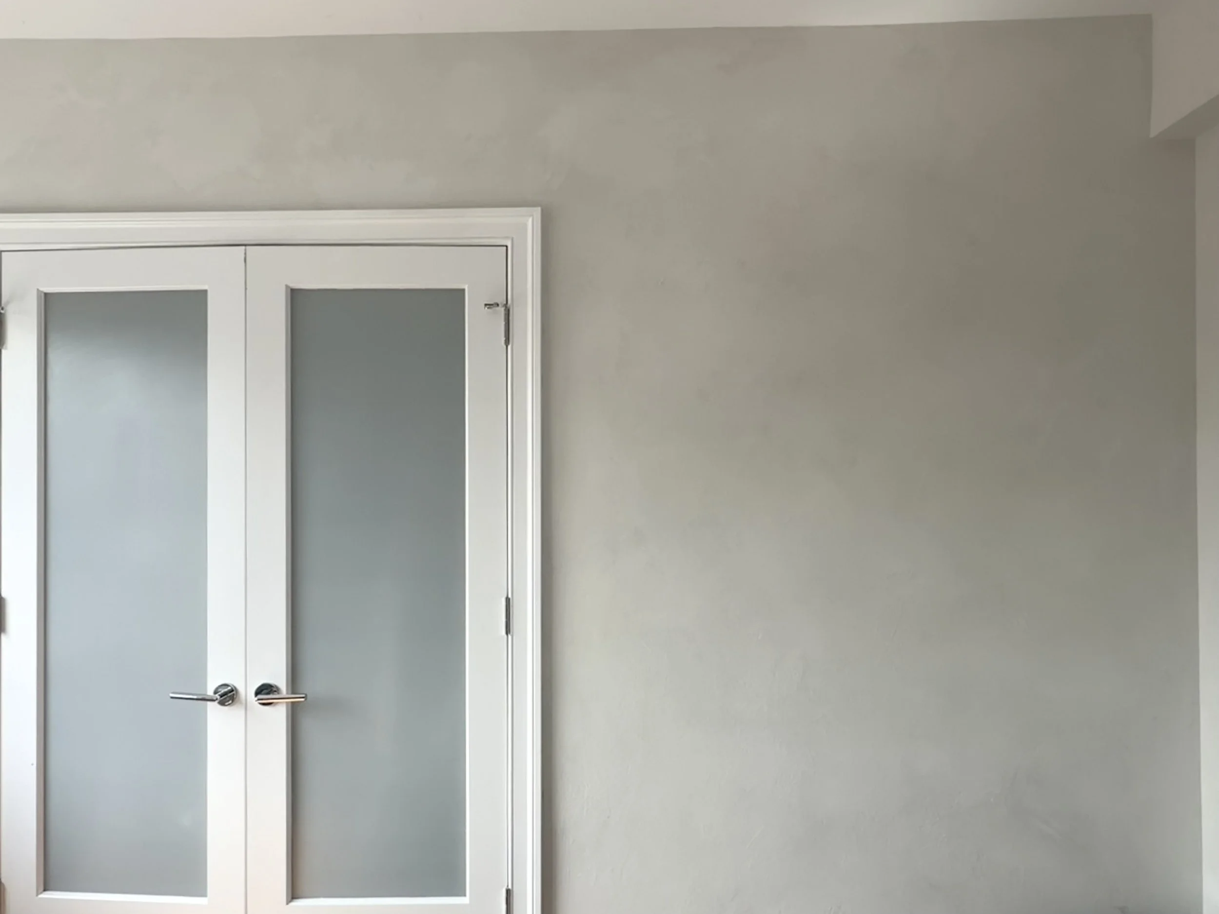 Cool gray limewashed wall with frosted glass door and bed — West Village bedroom, Limewall & Co.