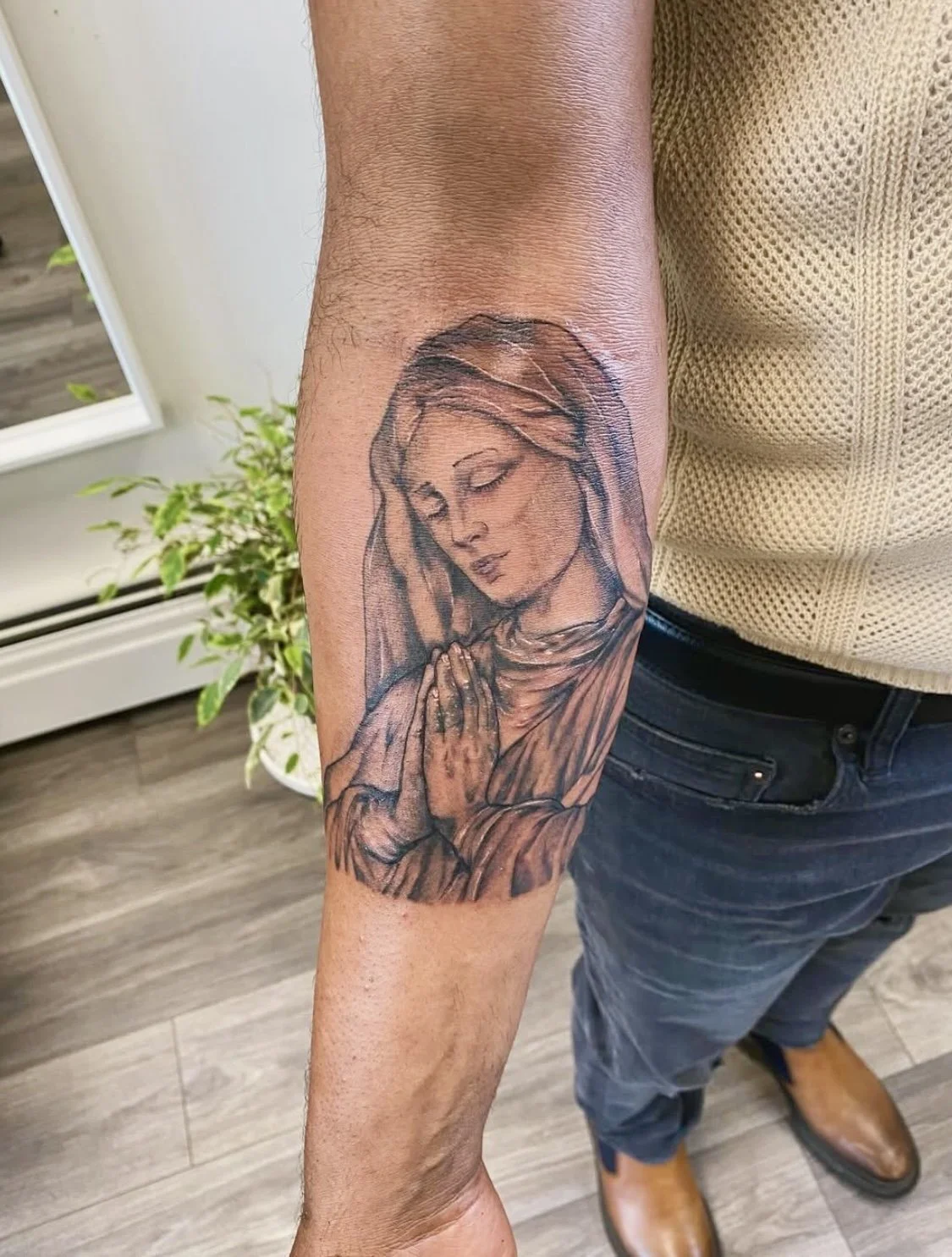 Tattoo of a praying woman with hands clasped, closed eyes, and a serene expression on her face.