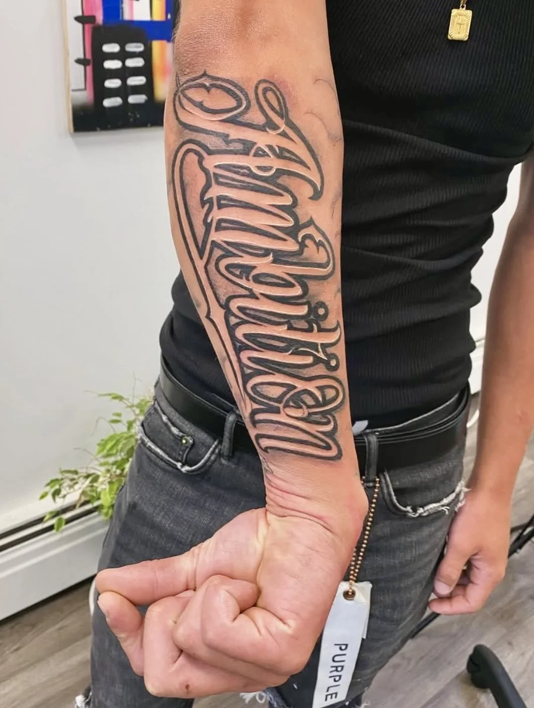 Tattoo of the phrase 'Love & Loyalty' in cursive script on a man's forearm.
