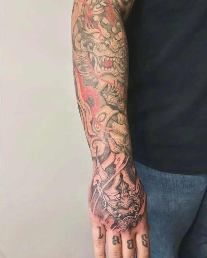 Tattoo sleeve featuring traditional Japanese style dragons and masks.