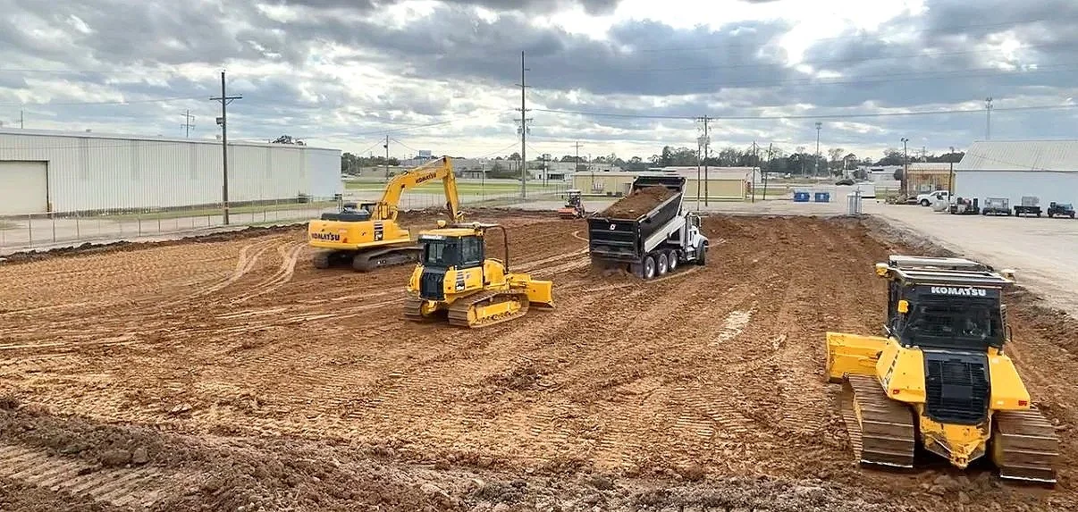 Construction site with bulldozers and a dump truck leveling and moving dirt.