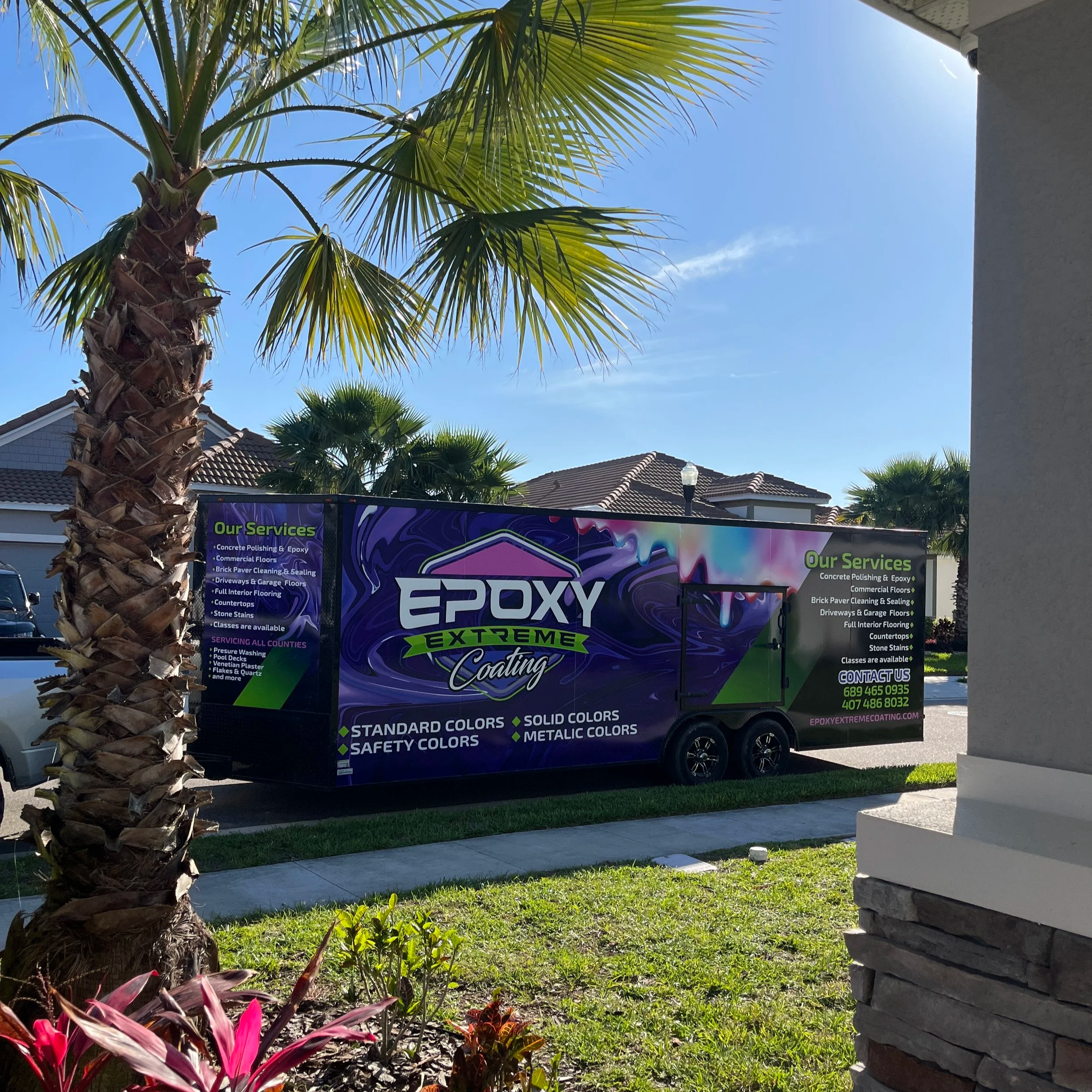 A colorful truck for Epoxy Extreme Coating parked on a street with palm trees and houses in the background.