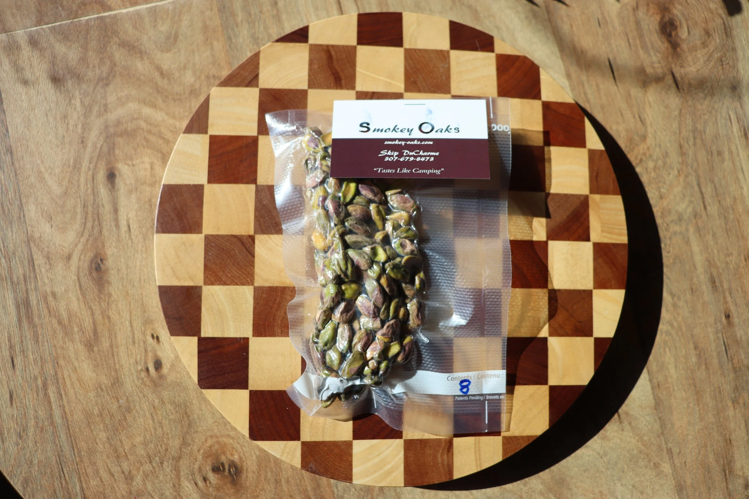A package of roasted pistachios on a checkered wooden chessboard table.