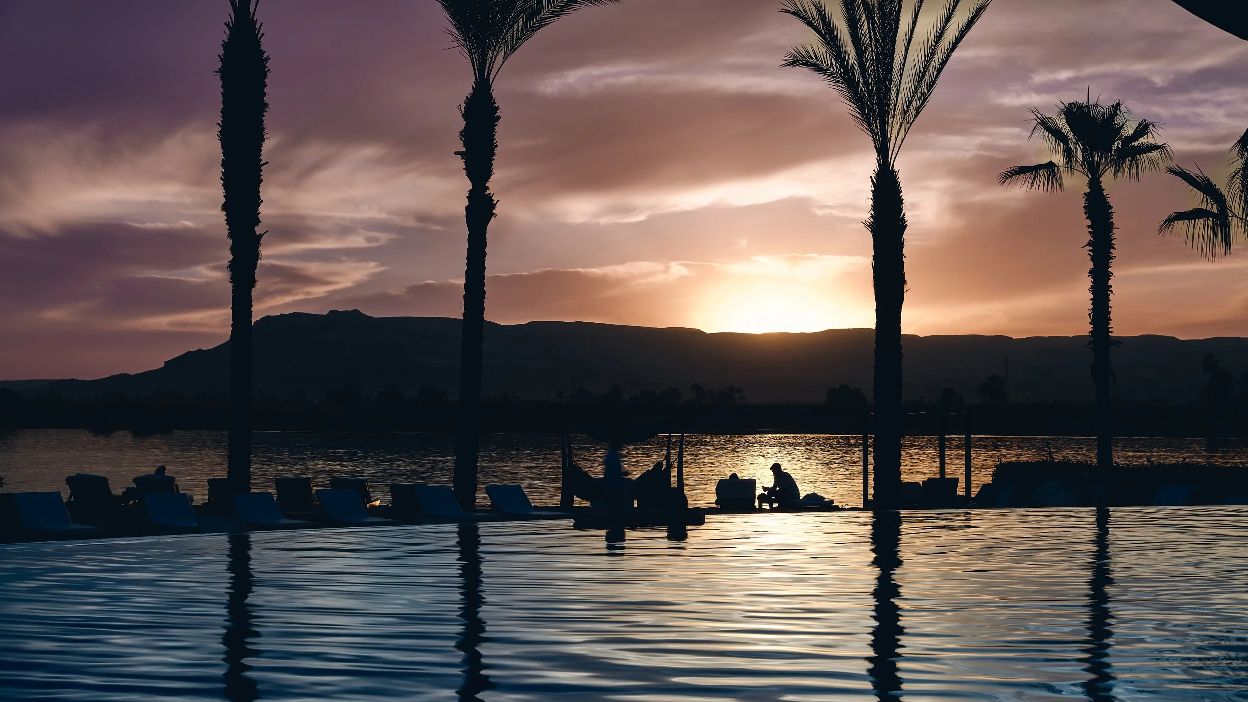 Sunset view of the Valley of the Kings from the Hilton Resort, with golden light spilling over the rugged desert hills.
