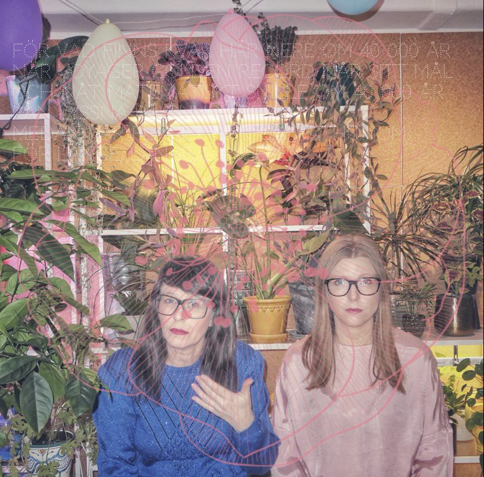 Bilden visar 500 mil i ett blomstrande rum med ballonger. Anna Charlotta bär blått och håller upp sin hand medan Christel bär rosa och tittar rakt fram. Båda är allvarliga. Fotot är taget av Sandra Löv.