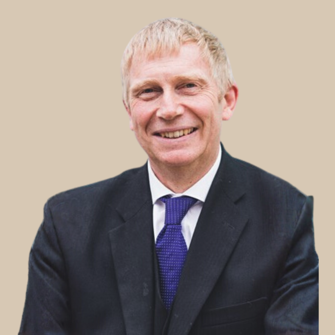 A smiling man in a black suit, white shirt, and purple tie.
