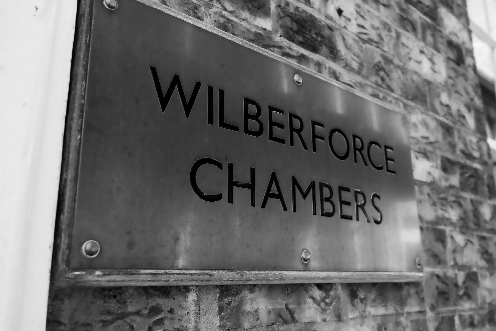 A metal plaque mounted on a brick wall with the inscription 'Wilberforce Chambers'.