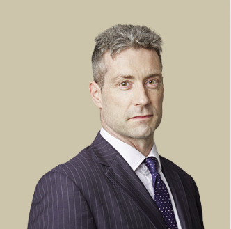 Portrait of a middle-aged man in a dark pinstripe suit and tie against a beige background.