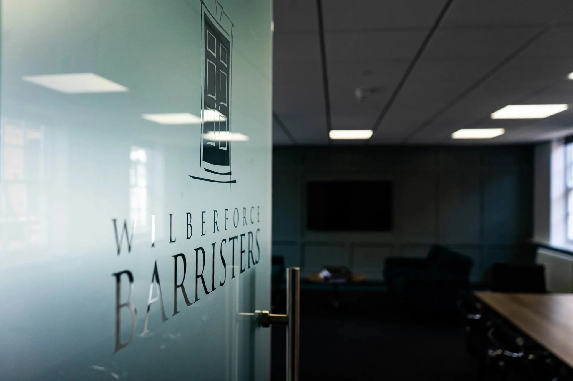 Glass door with Wilberforce Barristers logo in an office conference room.