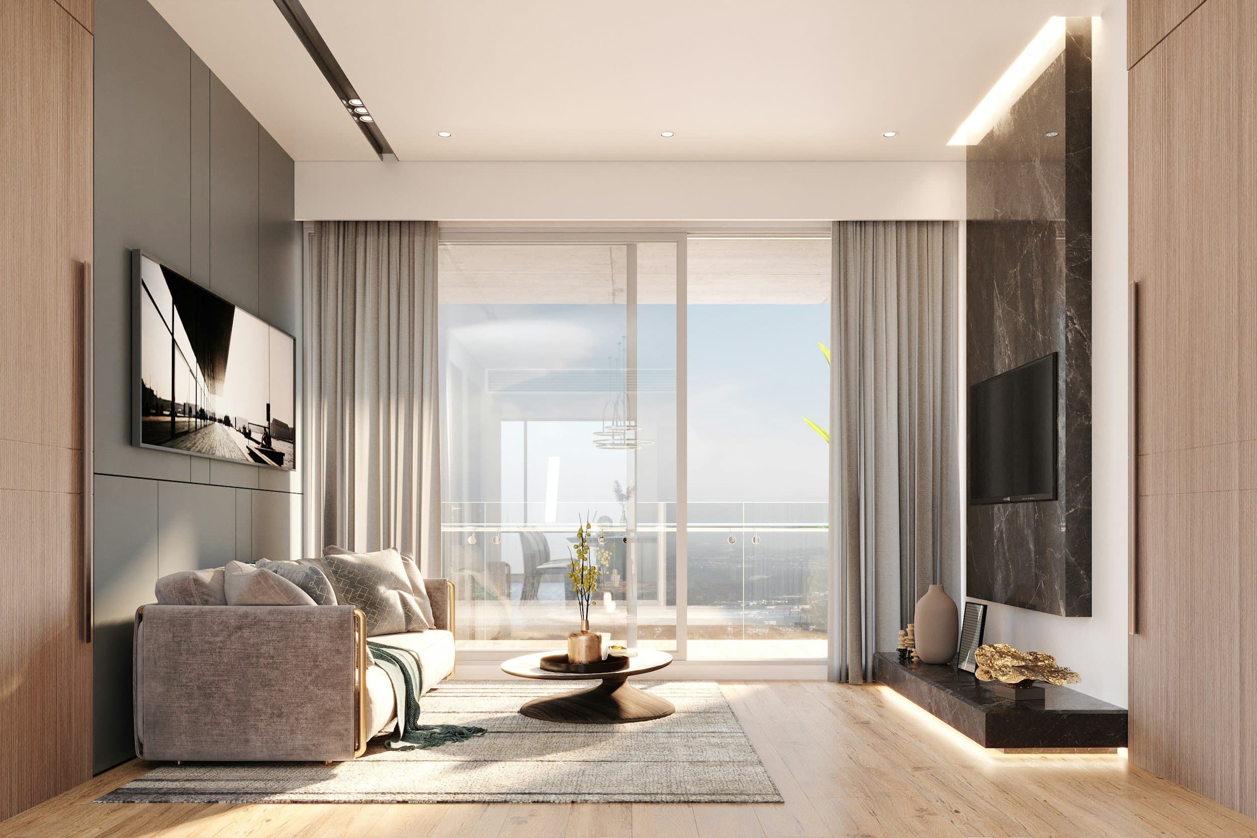 Modern living room with a gray couch, coffee table, large windows, two TVs, wood floors, and sunlight streaming in.