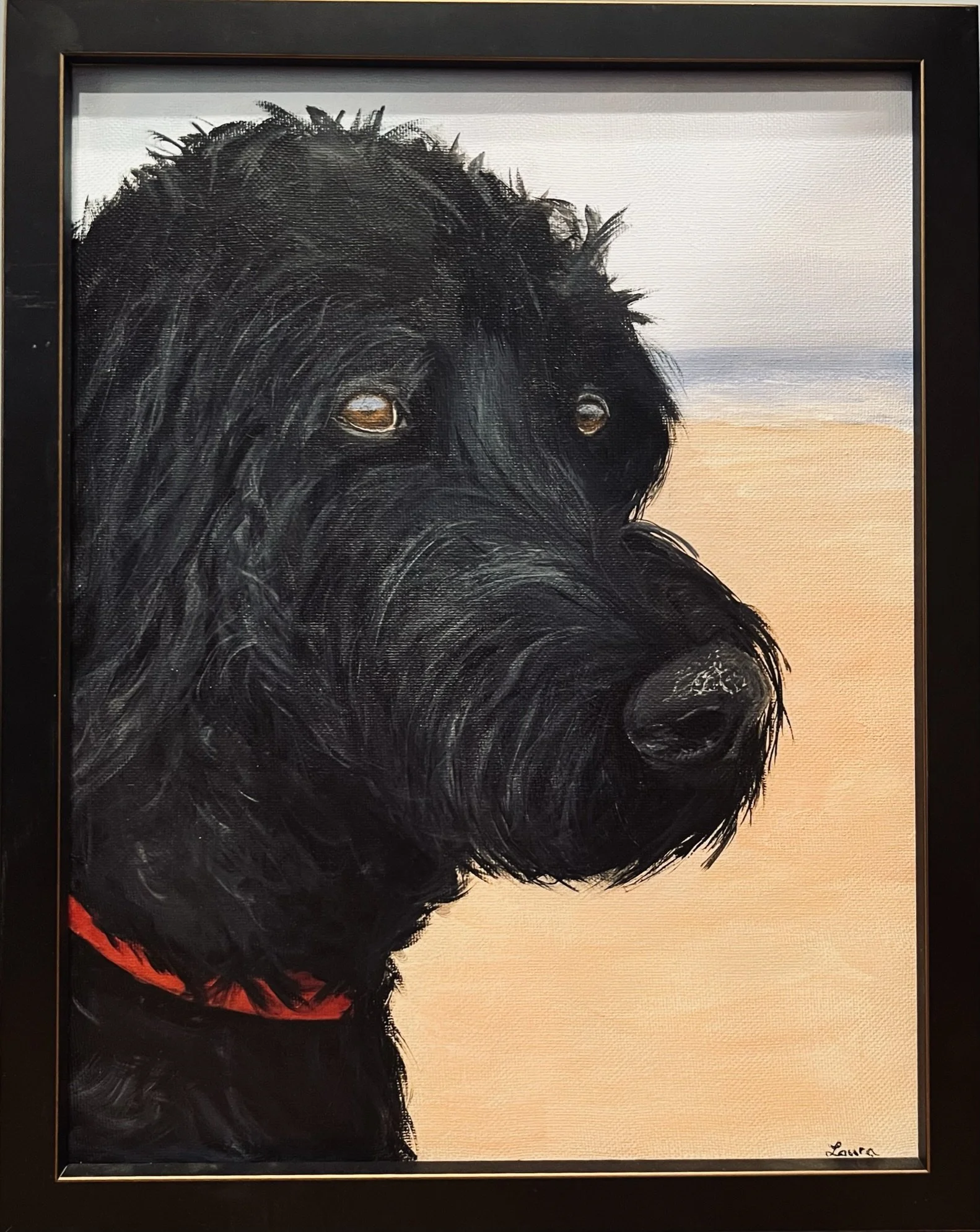 Painting of a black dog, likely a Labrador Retriever, with a red collar, sitting on a sandy beach with the ocean in the background.