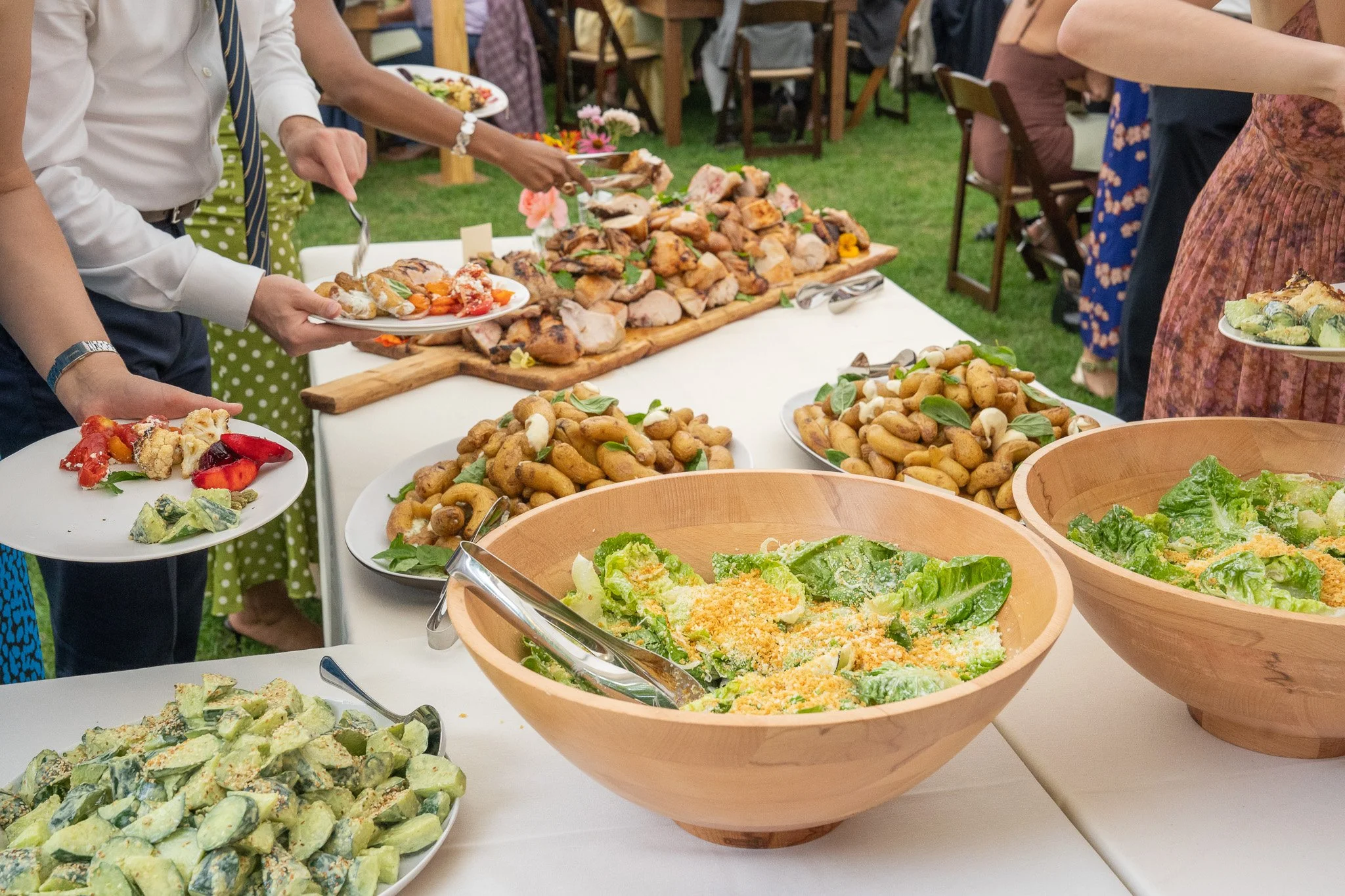 Wooden bowls of food, long wooden board with wood-fired grilled chicken. seasonal and colorful wedding food.