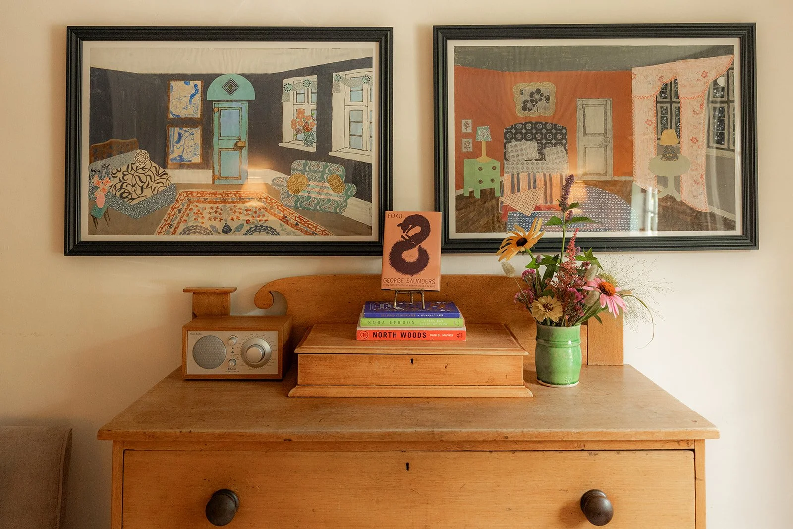 Wooden dresser in charming bedroom with original artwork and focus on natural materials.