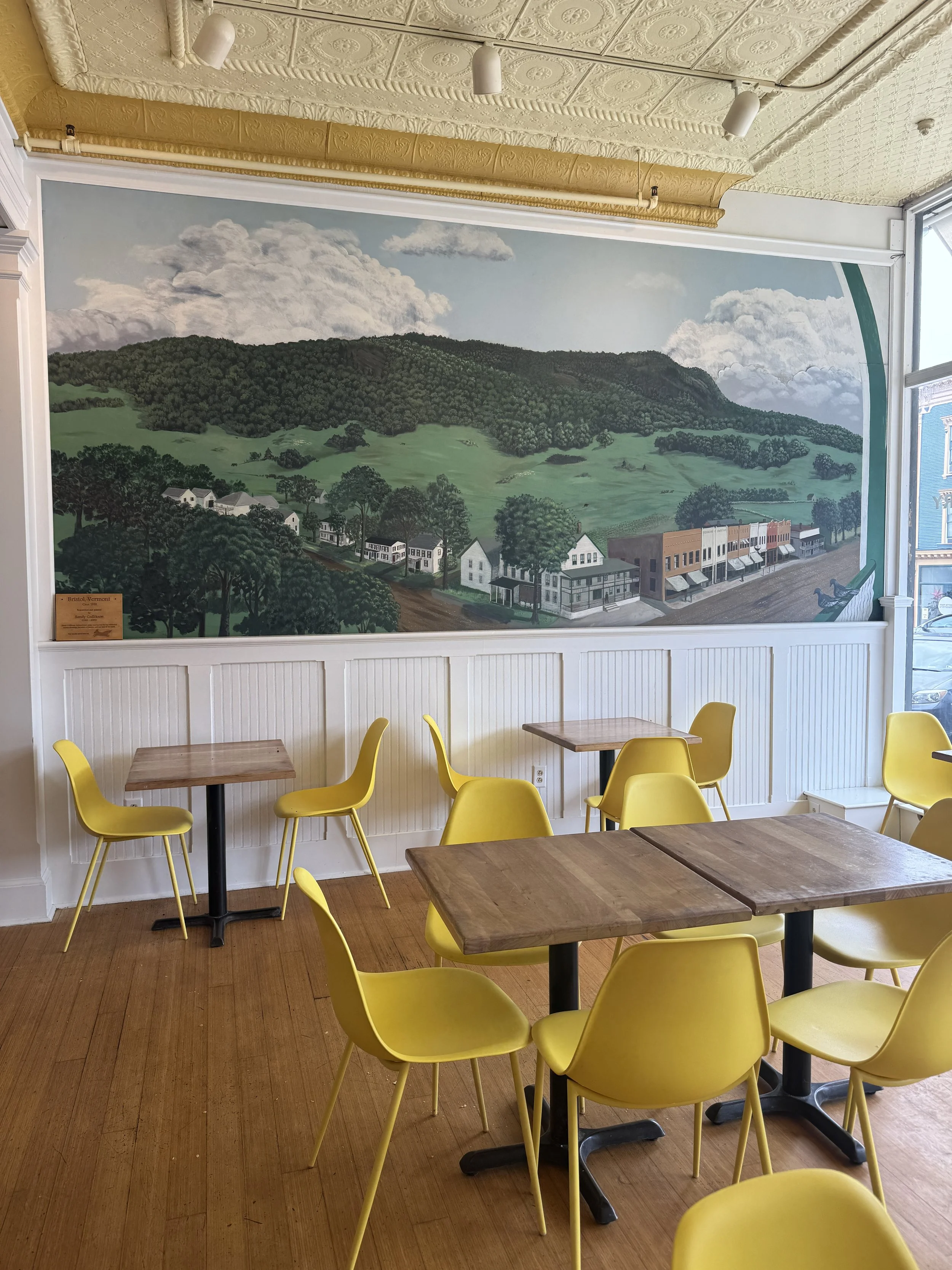 a mural of bristol and bright yellow chairs in minifactory, a coffee shop and brunch restaurant in bristol, vermont.