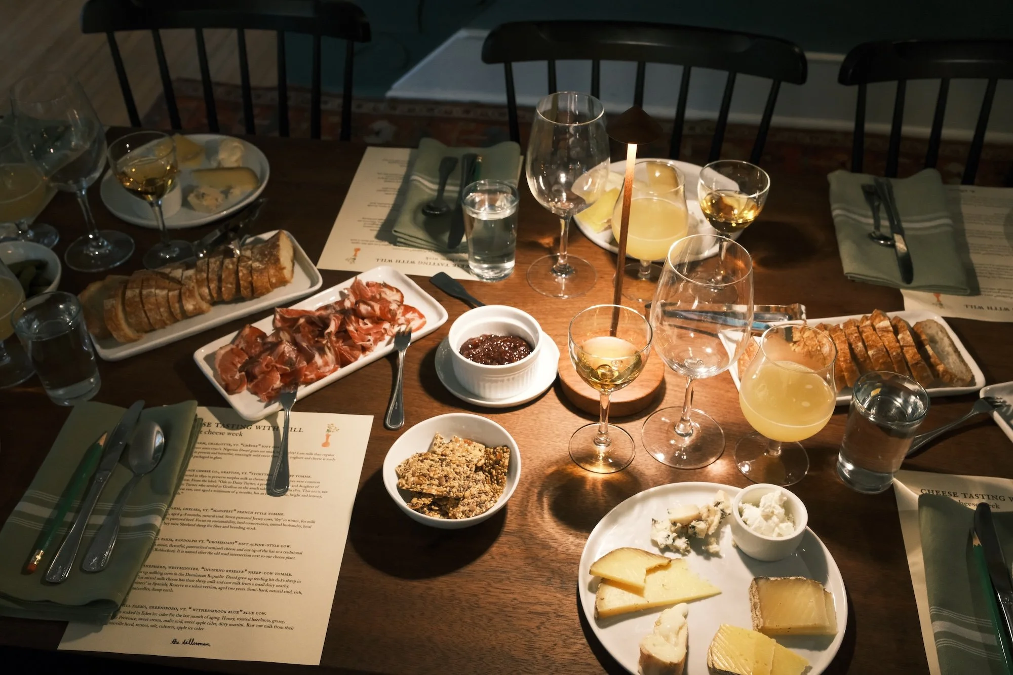 vermont cheese tasting in the parlor. a long farmhouse table is covered in cheeses, charcuterie, wine, and more. 