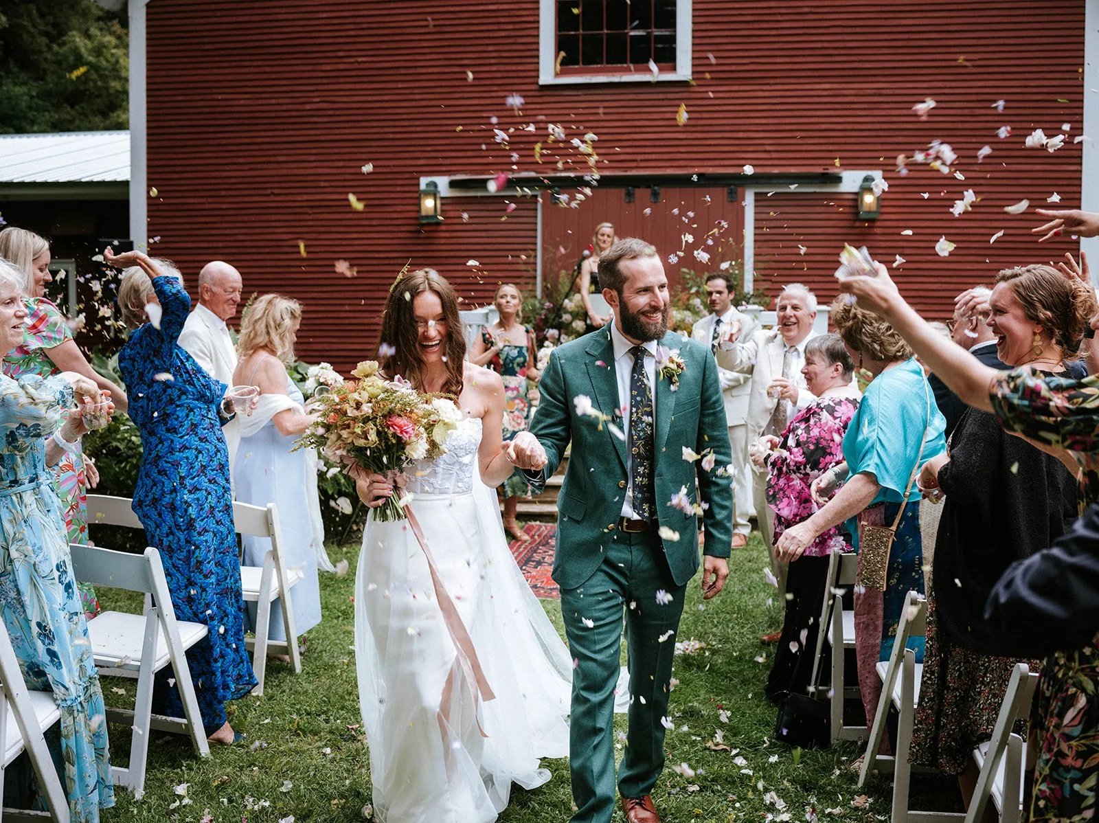 a couple walking down the aisle after just getting married in front of our historic red Vermont barn. 
