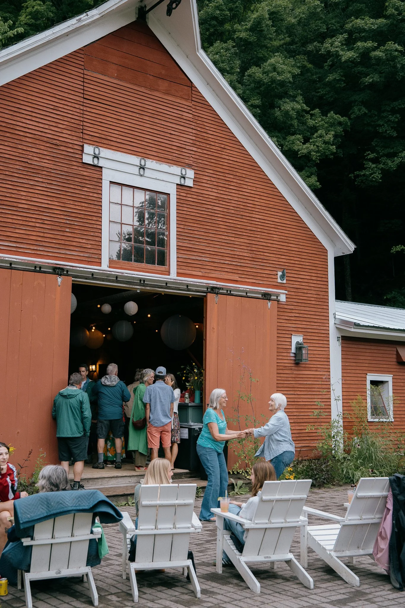two women dance and laugh outside a historic red vermont barn for live music night at the tillerman inn and restaurant in bristol vermont