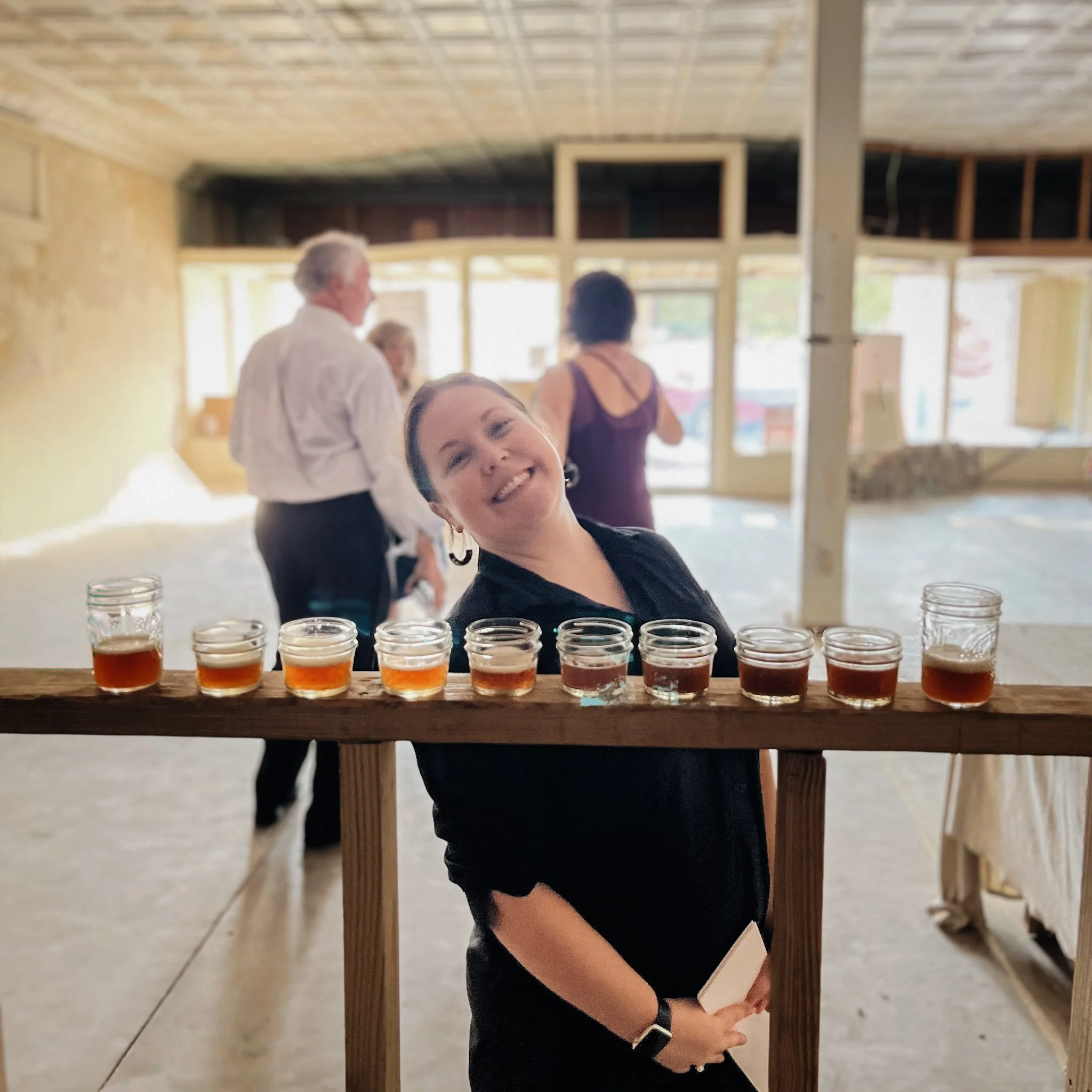 Green grapevine leaves growing along a trellis in sunlight with a blue sky in the background.