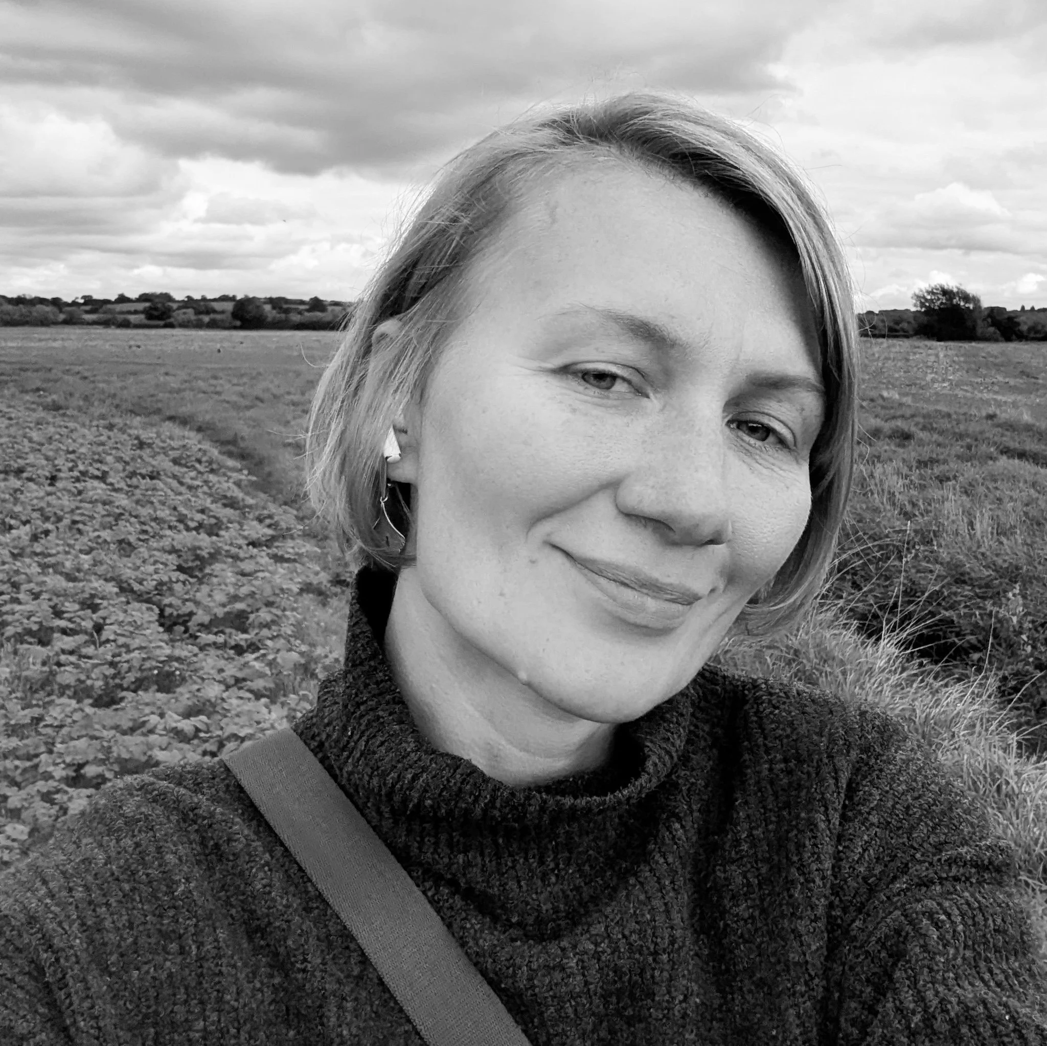Image of Tanya from the shoulders up, smiling in a field.