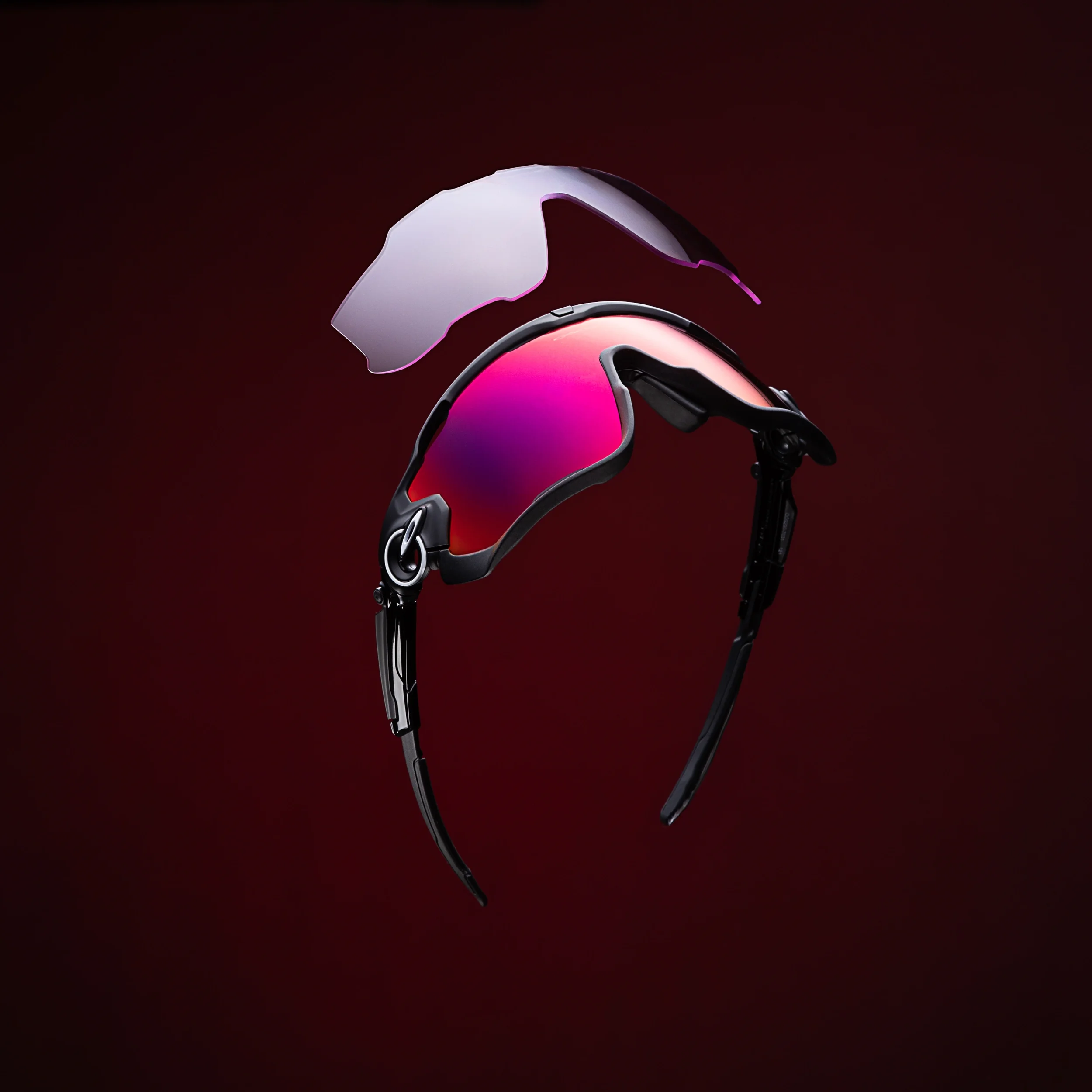 high end commercial product photography studio image of sports oakley sunglasses on a dark red background