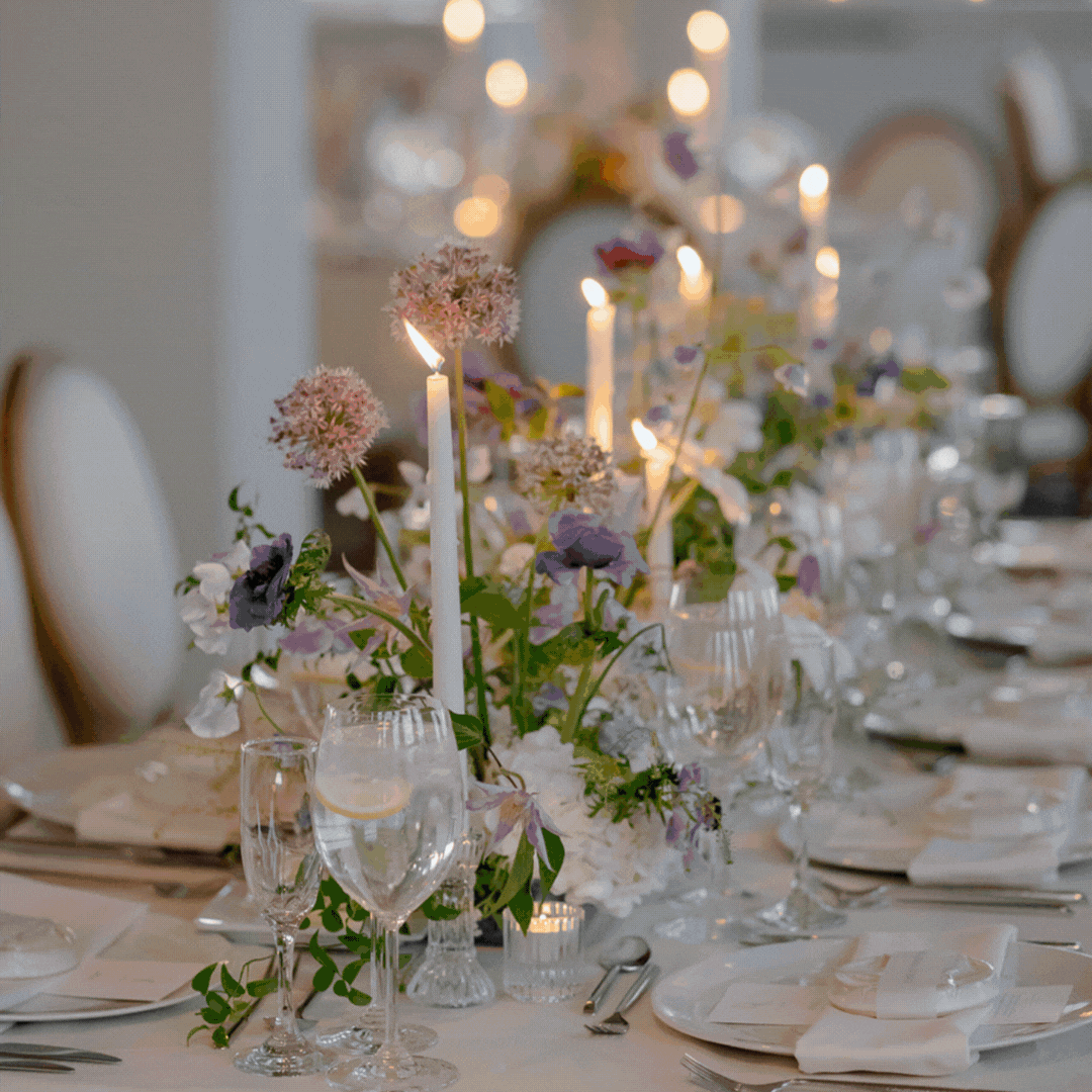Elegant dining table decorated with candles and purple and white flowers