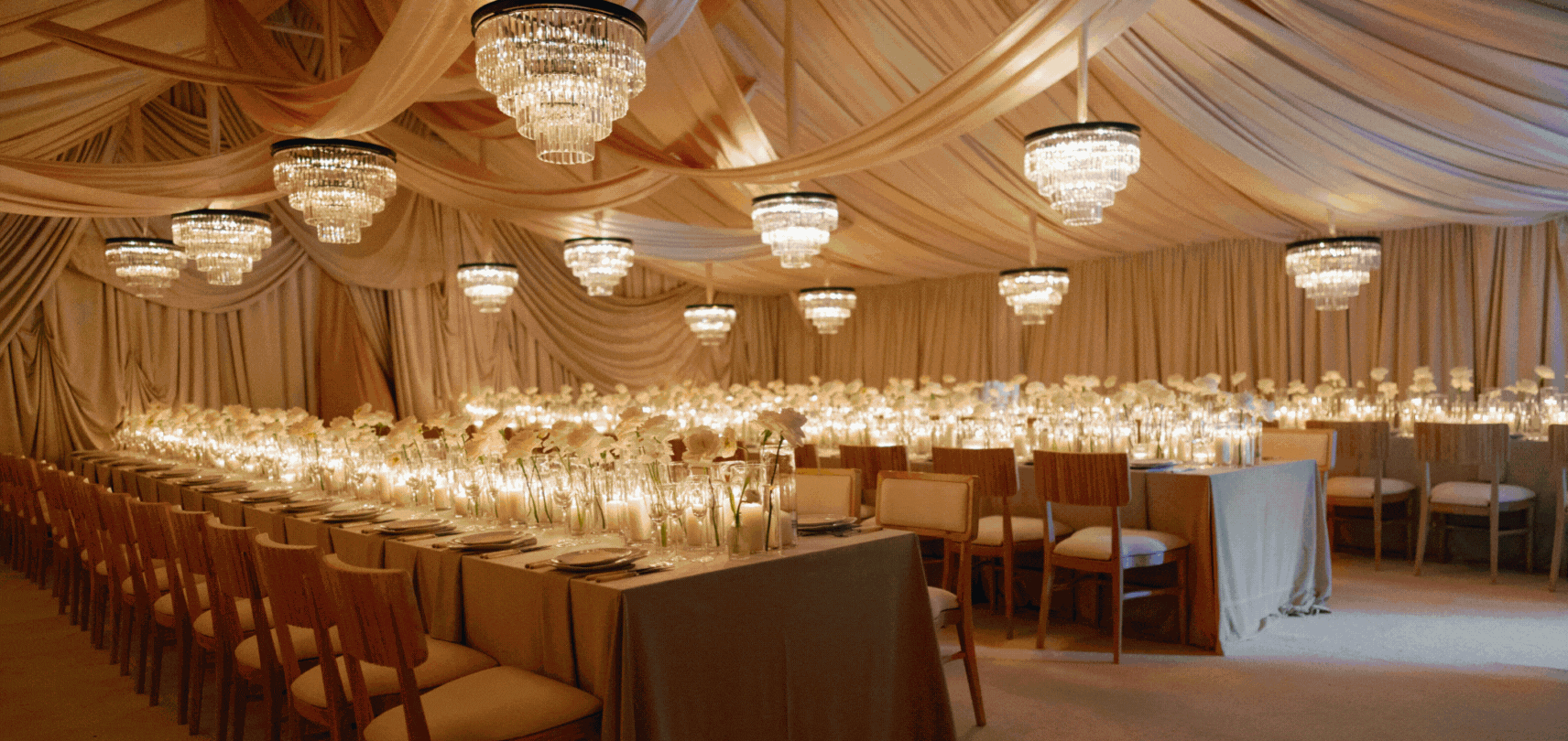 Elegant banquet hall decorated with draped curtains, chandeliers, and floral centerpieces.