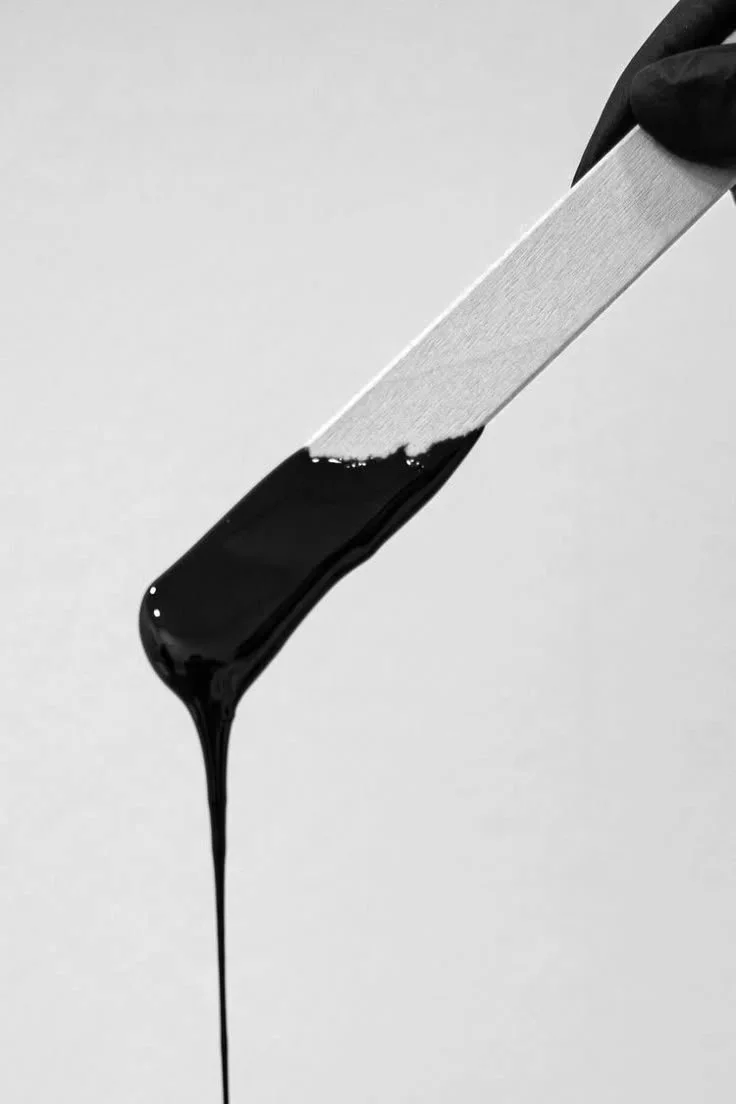 body wax dripping from a wood stick
