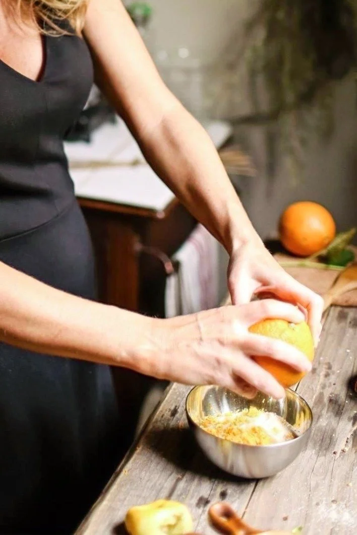 A set of hands working to juice an orange at a wooden apothecary table.