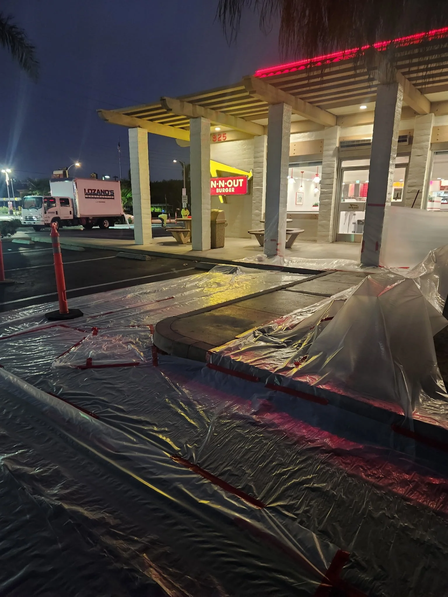 Night concrete work outside an In-N-Out Burger in Placentia, with the surrounding area masked off and a Lozano's truck on site