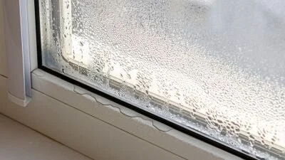 Close-up of a frosted, foggy window with condensation and water droplets.