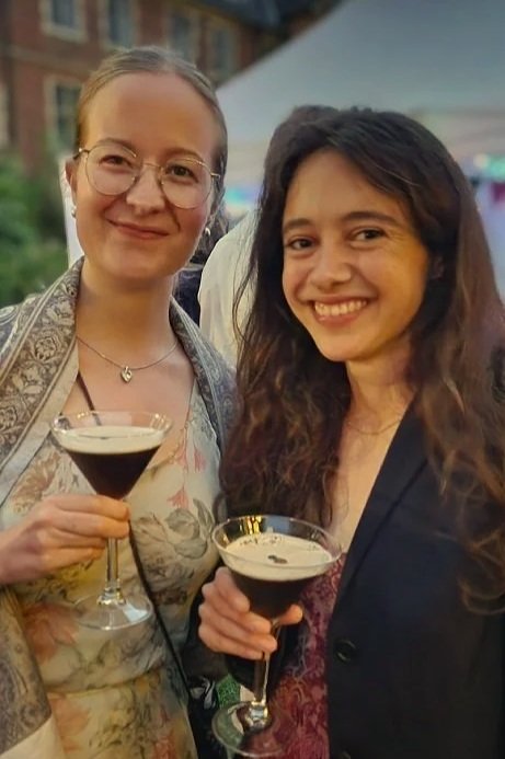 two women holding cocktails in fancy dress